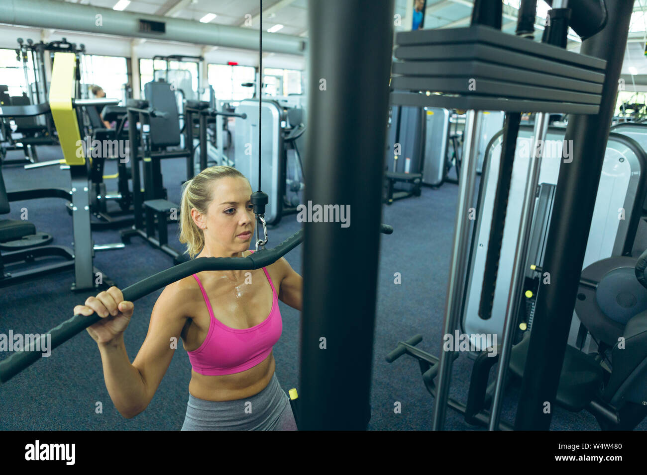 L'exercice avec l'athlète féminine déroulant lat machine in fitness studio Banque D'Images