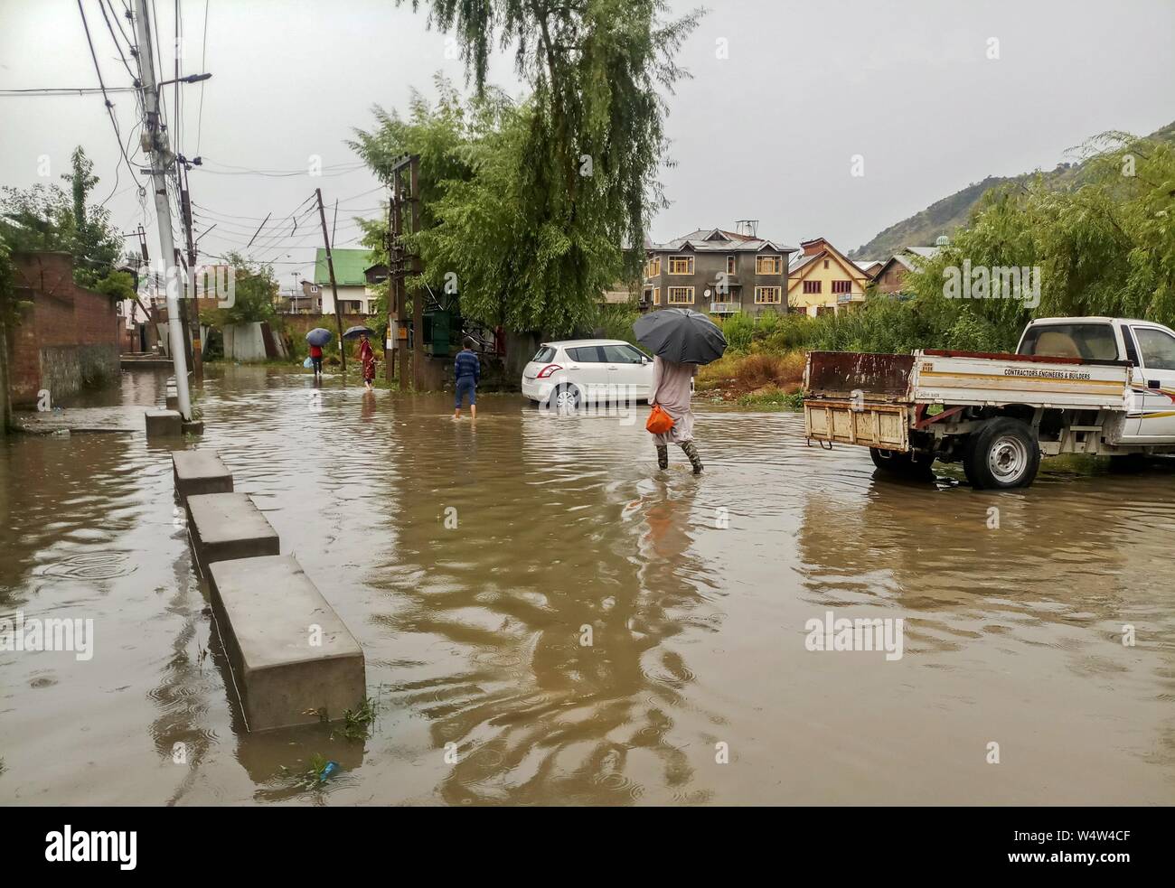 Srinagar, Inde. Le 25 juillet, 2019. Au cours de la wade résidents de fortes pluies dans la région de Srinagar.De fortes pluies ont provoqué l'engorgement dans de nombreux domaines de Srinagar exposant le mauvais drainage de la ville. Le temps le ministère a prévu plus de précipitations dans de nombreuses régions de la vallée dans les prochaines 24 heures. Credit : SOPA/Alamy Images Limited Live News Banque D'Images