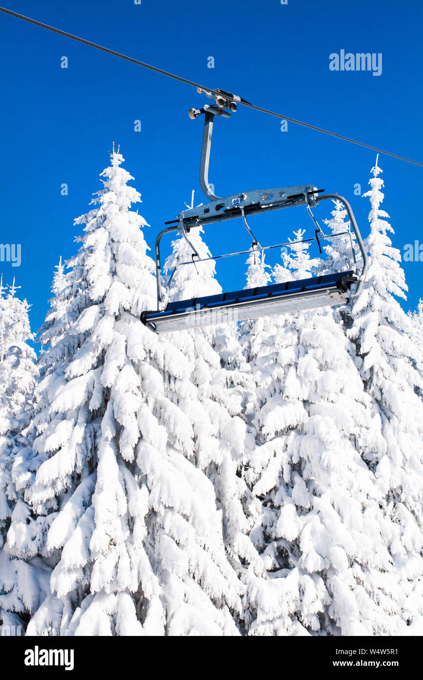 Ski libre avec télésiège vide, ciel bleu et blanc snowy pins au soleil d'hiver Banque D'Images