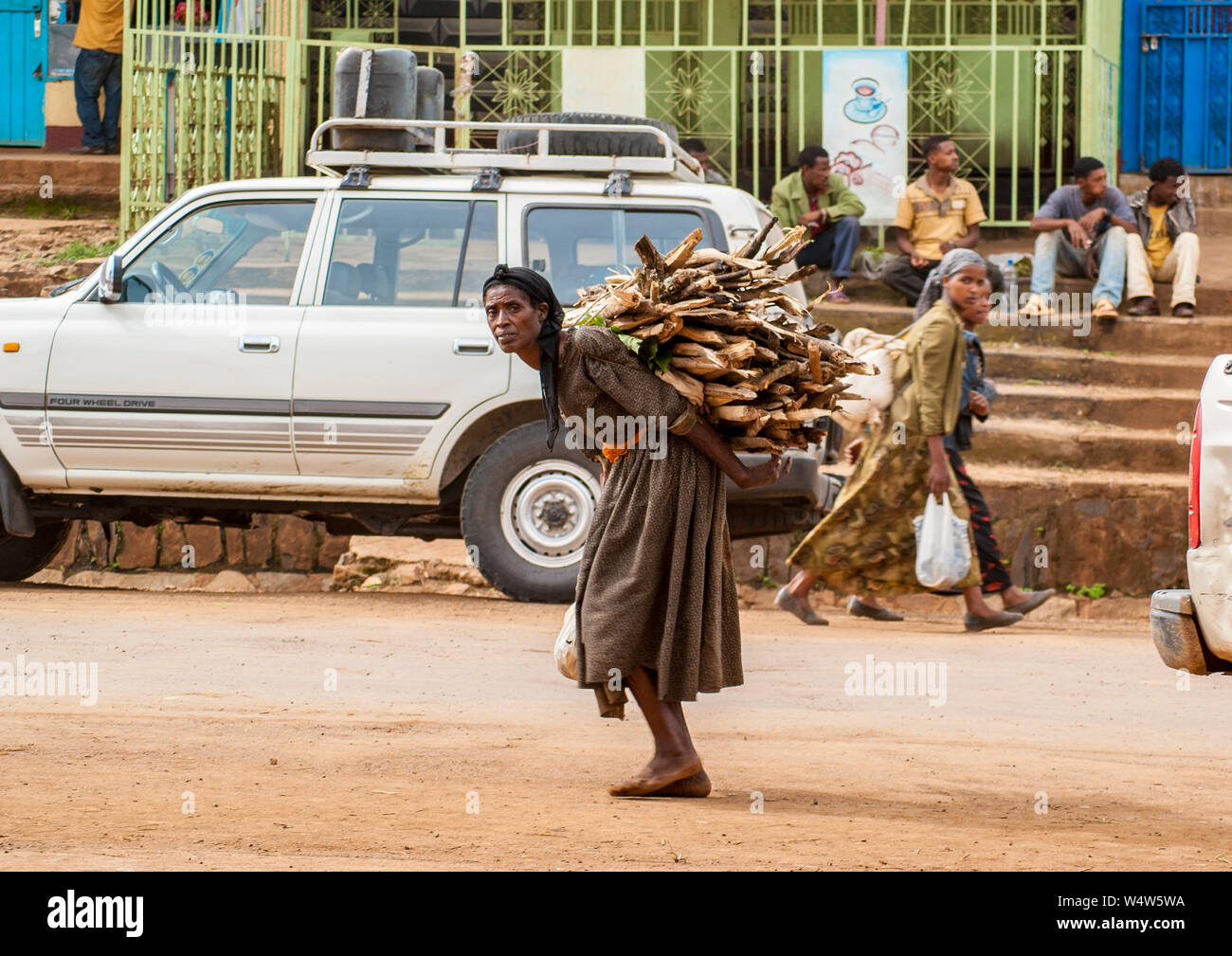 Des femmes portant d'énormes tas de bois de chauffage sur son dos, Bedele, Ethiopie Banque D'Images