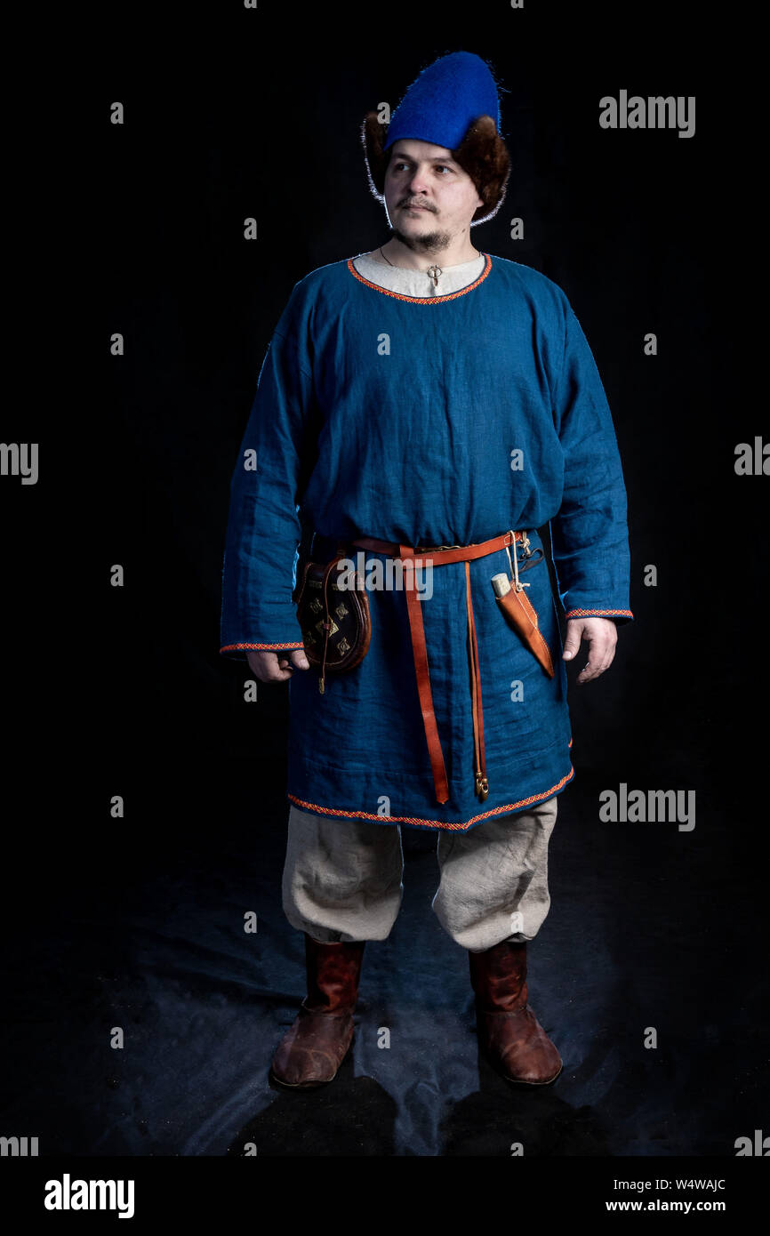 Un homme vêtu de vêtements décontractés de l'Âge des Vikings (hat, caftan,  pantalon, chapeau) se dresse sur un fond noir. Reconstitution historique de  la période du 9 Photo Stock - Alamy