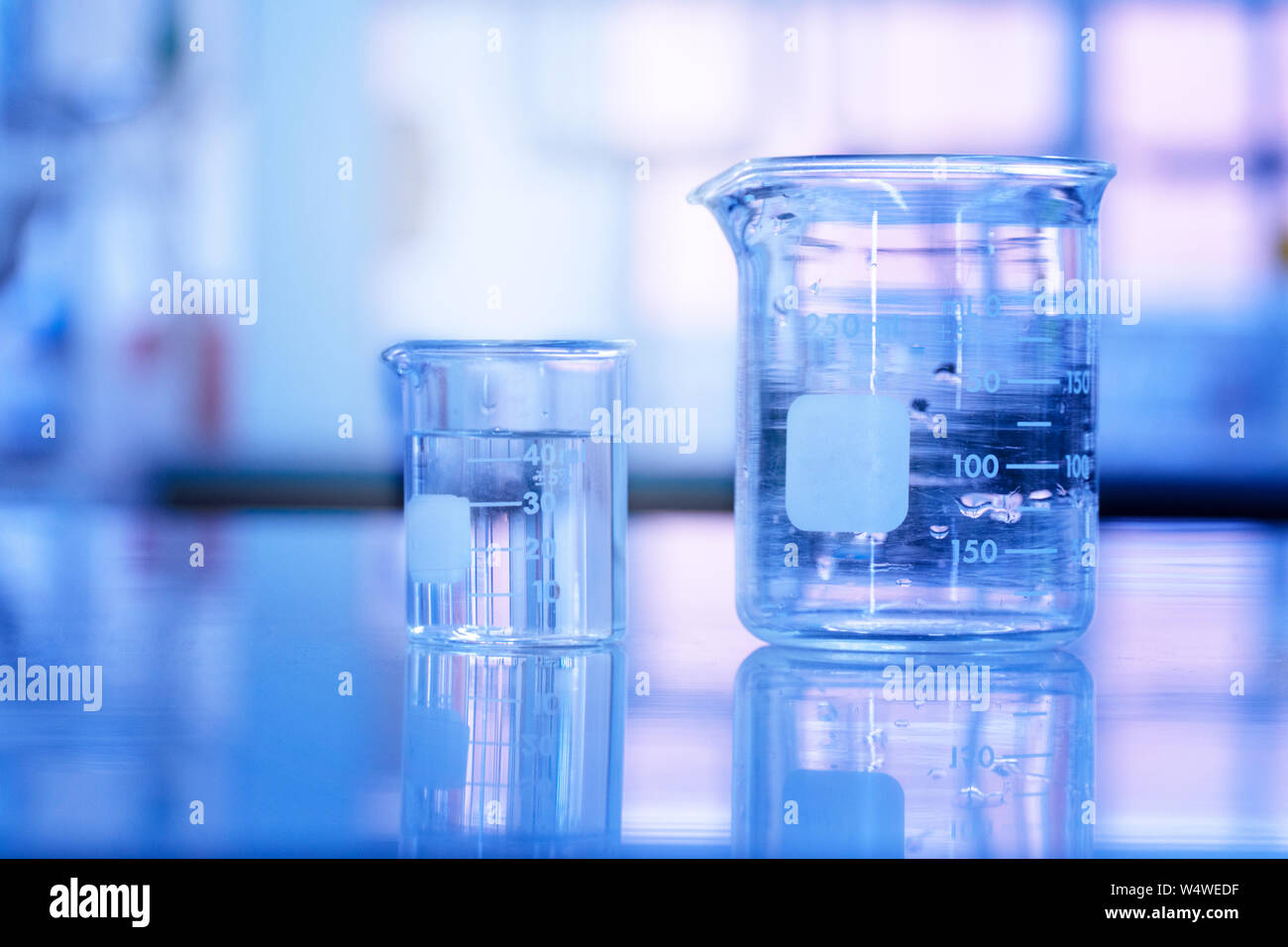 Deux bécher en verre avec de l'eau dans l'arrière-plan bleu medical science laboratory Banque D'Images