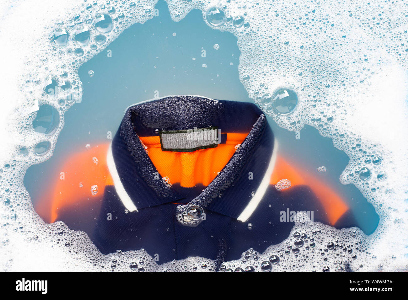 Polo shirt faire tremper dans de l'eau détergent en poudre la dissolution, lave-linge doux. Concept de blanchisserie Banque D'Images