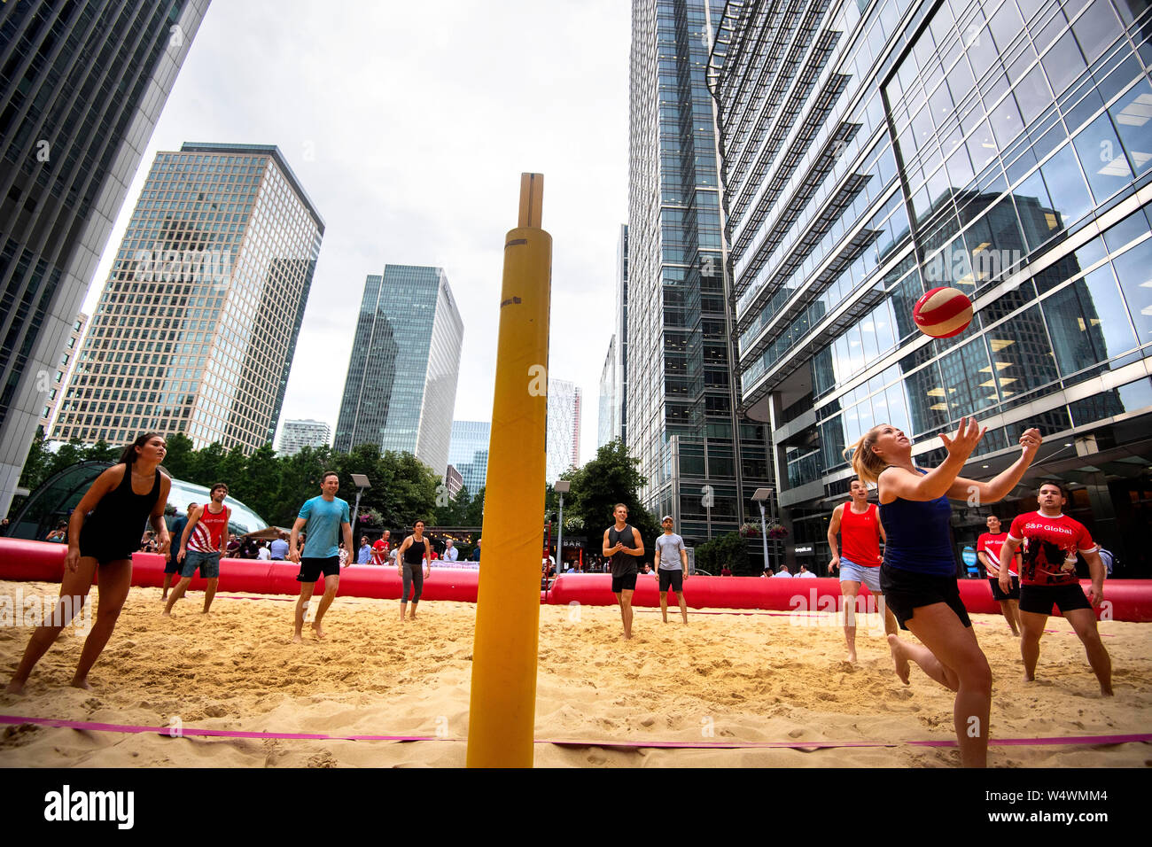 Les gens de faire une partie de volley-ball dans une cour de pop up à Canary Wharf, Londres, après plus de 200 tonnes de sable vint combler un espace entre les grands bâtiments financiers. Banque D'Images