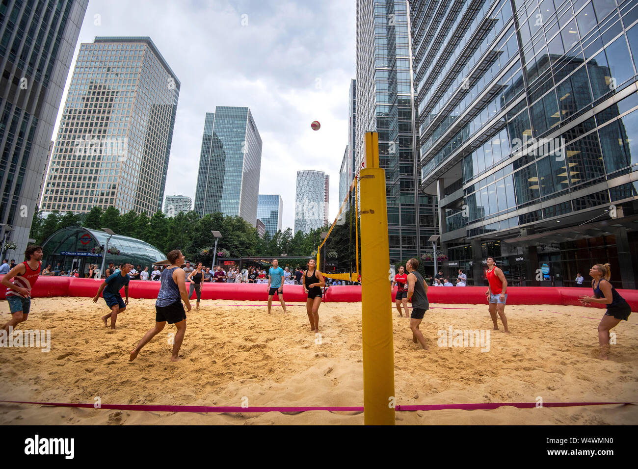 Les gens de faire une partie de volley-ball dans une cour de pop up à Canary Wharf, Londres, après plus de 200 tonnes de sable vint combler un espace entre les grands bâtiments financiers. Banque D'Images