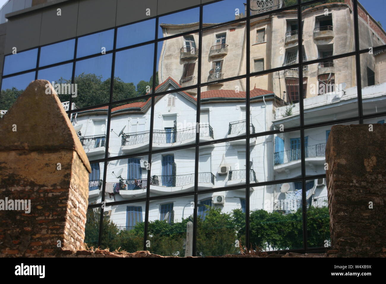 Vieux mur de ville Saldae ruines, en face de l'immeuble moderne Port Bejaia, reflétant une maison coloniale française. Banque D'Images