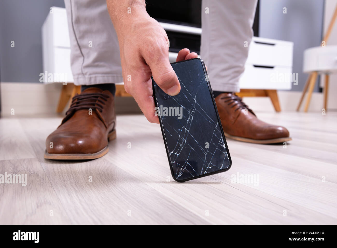 La main de l'homme prendre le téléphone mobile à écran cassé Banque D'Images