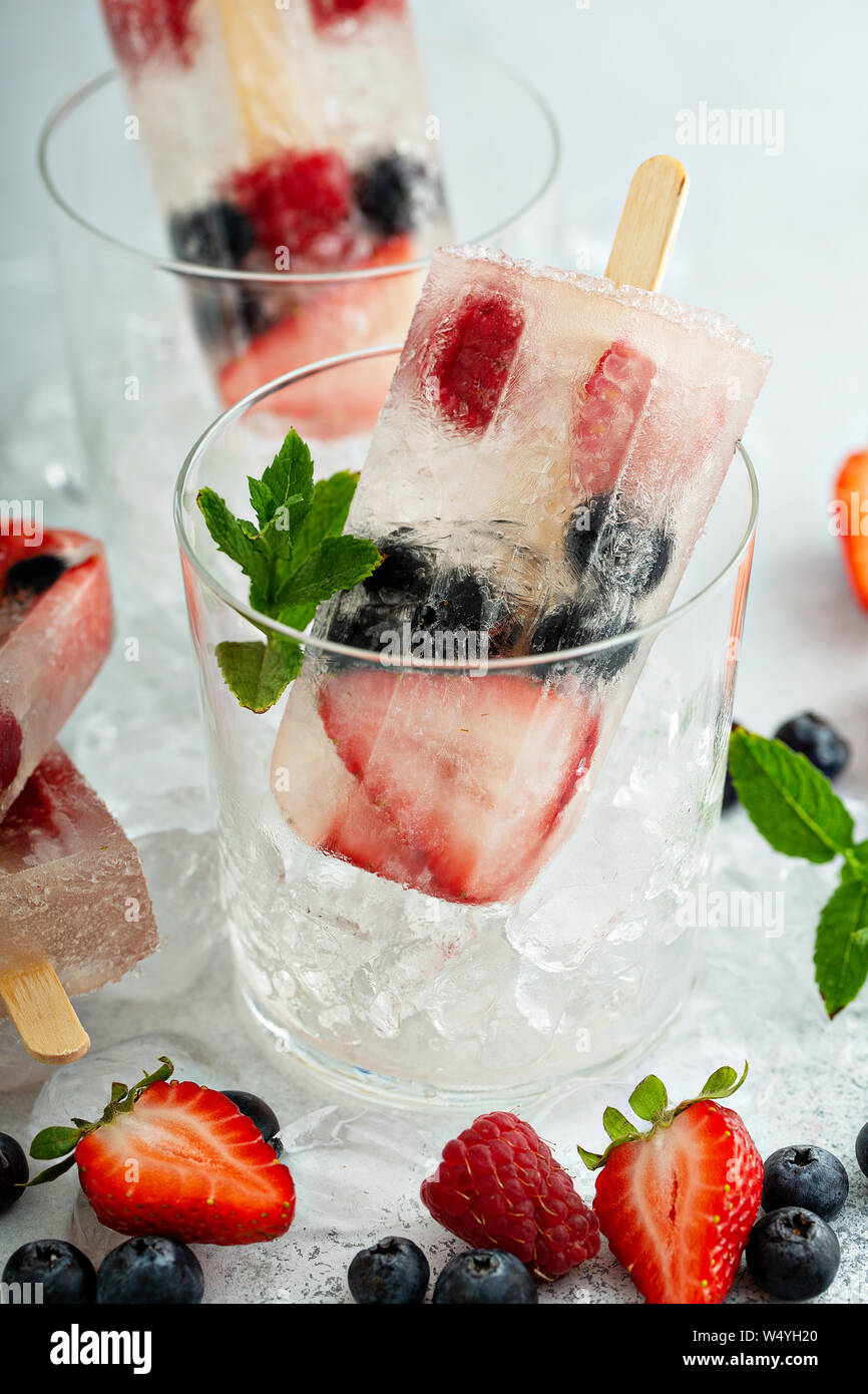 Sucettes glacées au champagne avec des fraises, framboises et bleuets Banque D'Images