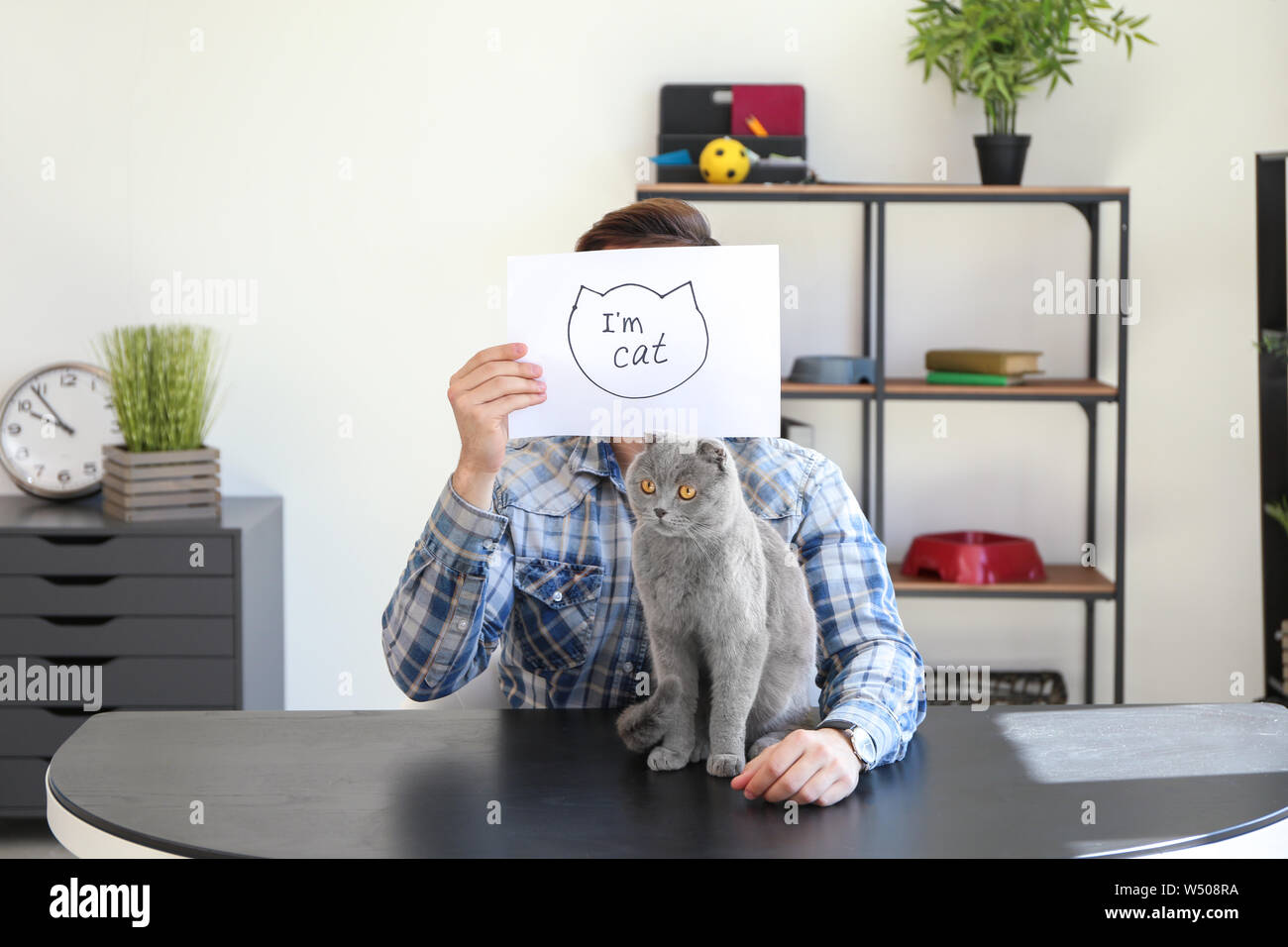 Jeune homme tenant le papier avec texte et dessin JE SUIS CAT et son animal mignon Banque D'Images