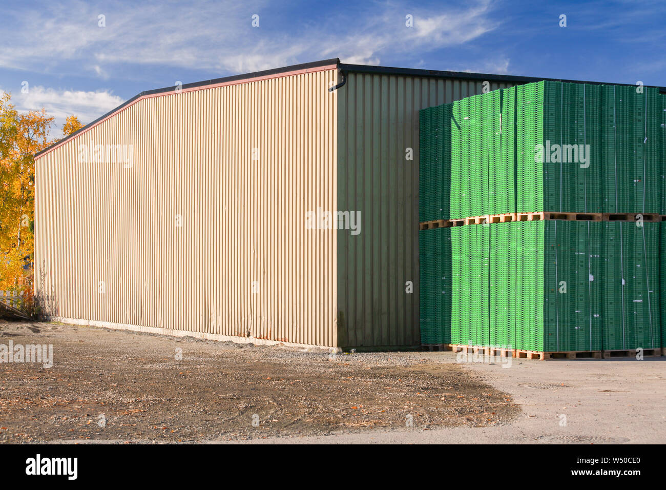 Coin d'un bâtiment de stockage et des piles de palettes d'expédition en plastique vert. Port de Levanger, Norvège Banque D'Images