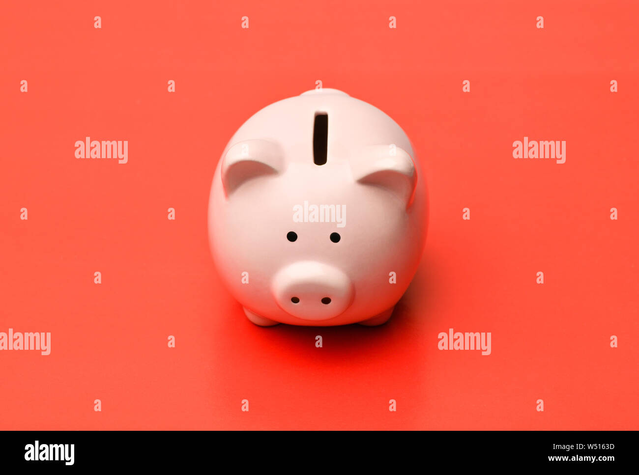 Pink Piggy Bank se trouve au centre sur un fond rouge avec une ombre. Photographie horizontale Banque D'Images
