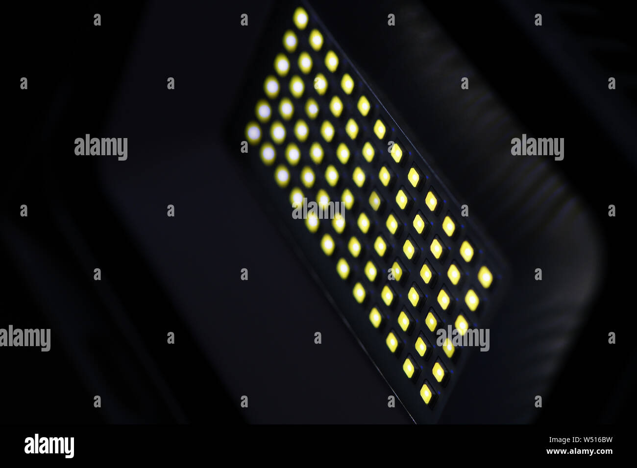 Une diode de projecteurs rectangulaires gris dans une pièce sombre s'allume avec lumière jaune. Arrière-plan flou Banque D'Images