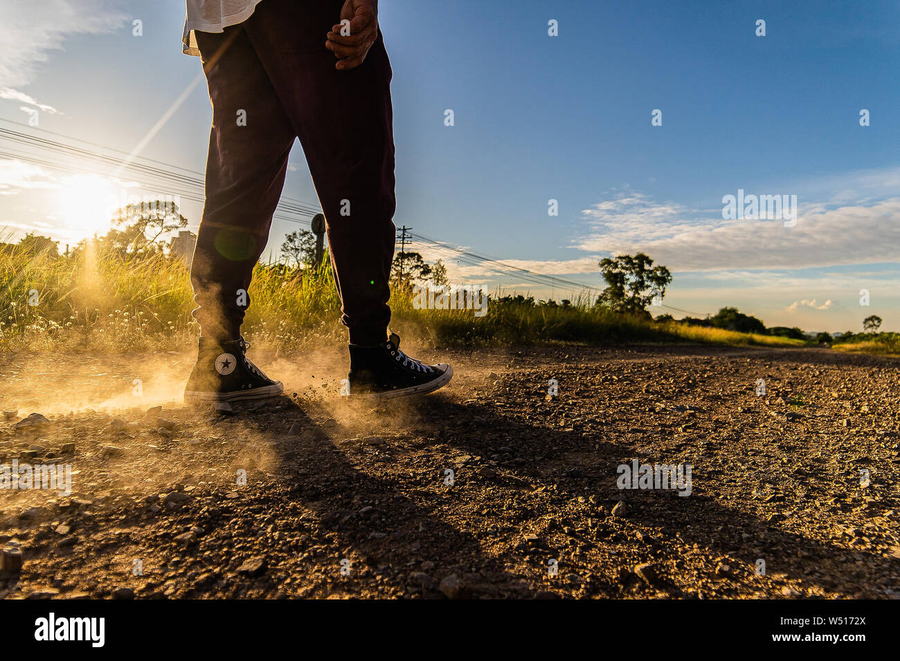Homme portant des chaussures de marche le long du chemin de fer sur route poussiéreuse et de sable sur l'après-midi ensoleillé Banque D'Images