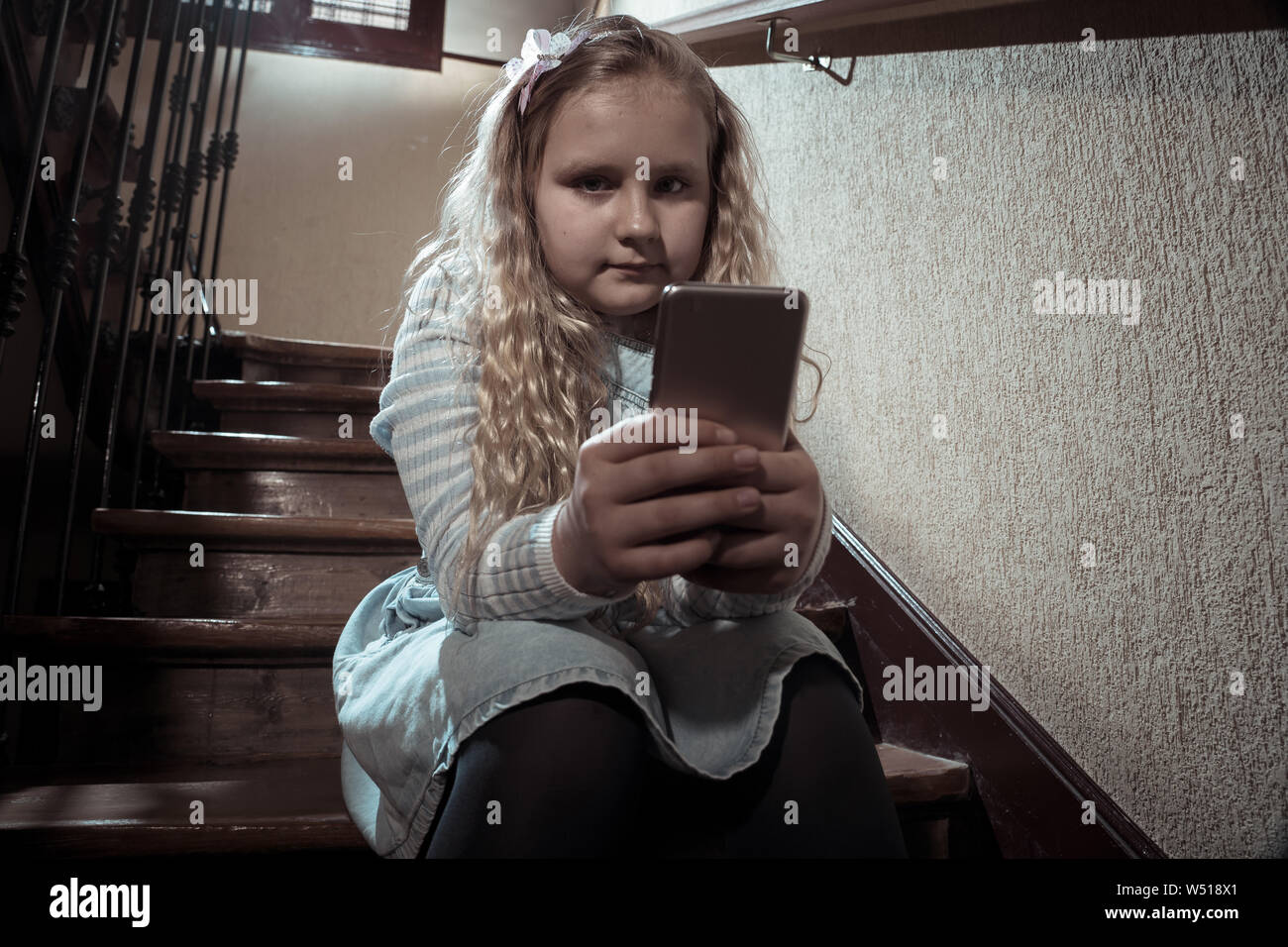 Déprimé triste jeune fille victime de cyberintimidation par smart mobile phone sitting on stairs vous sentir seul, malheureux, sans espoir et d'abus. Un enfant intimidé Banque D'Images