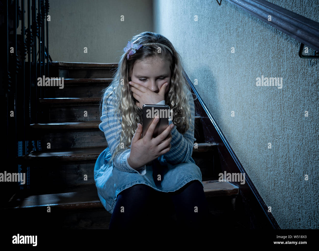 Déprimé triste jeune fille victime de cyberintimidation par smart mobile phone sitting on stairs vous sentir seul, malheureux, sans espoir et d'abus. Un enfant intimidé Banque D'Images