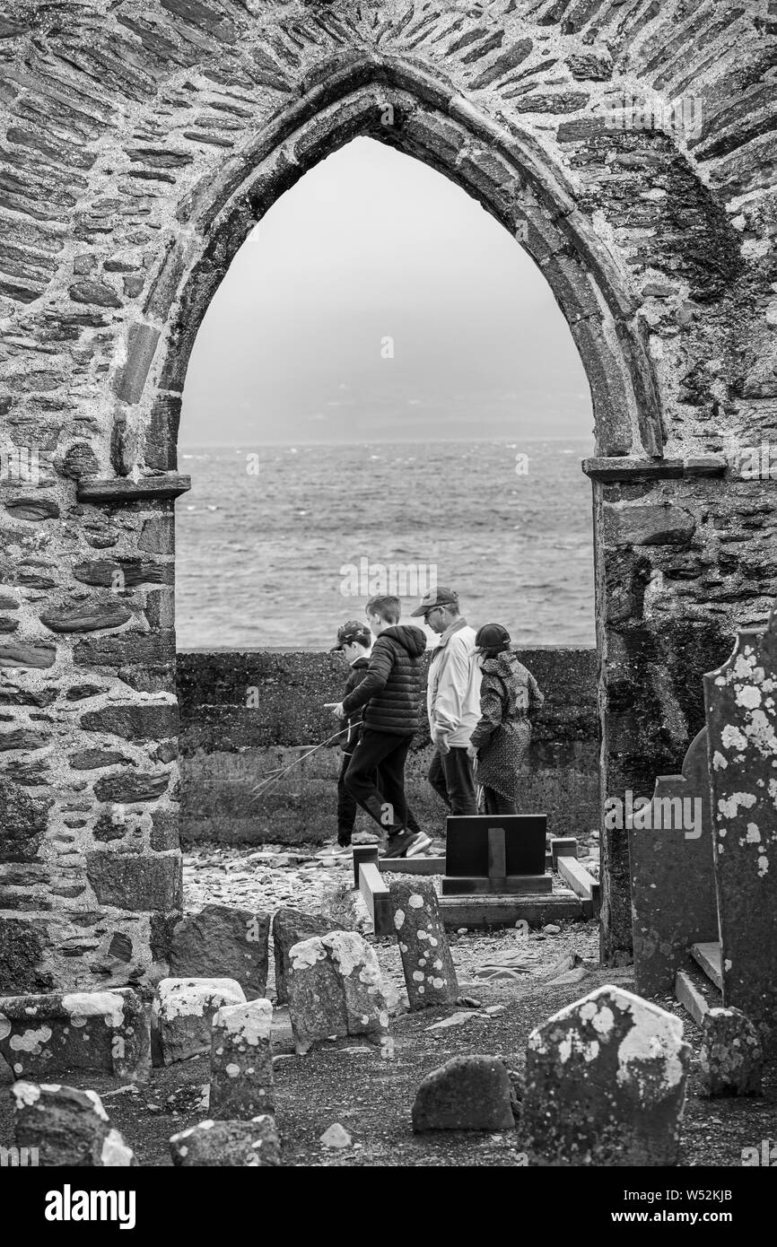 Groupe de la famille passant par une voûte en pierre de l'abbaye en ruine dans Ballinskelligs, comté de Kerry, Irlande Banque D'Images