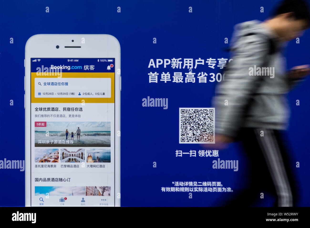Un passager passe devant une publicité pour le site de réservation en ligne Booking.com à une station de métro à Shanghai, Chine, 29 décembre 2018. Booki Banque D'Images