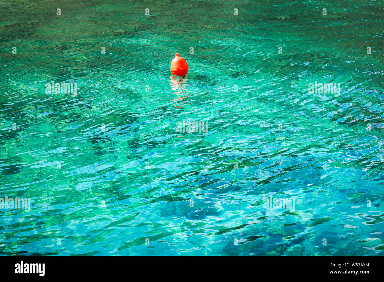 Contexte, le motif ou la texture d'une bouée rouge flottant sur l'eau turquoise. Concept de nager en toute sécurité. Banque D'Images