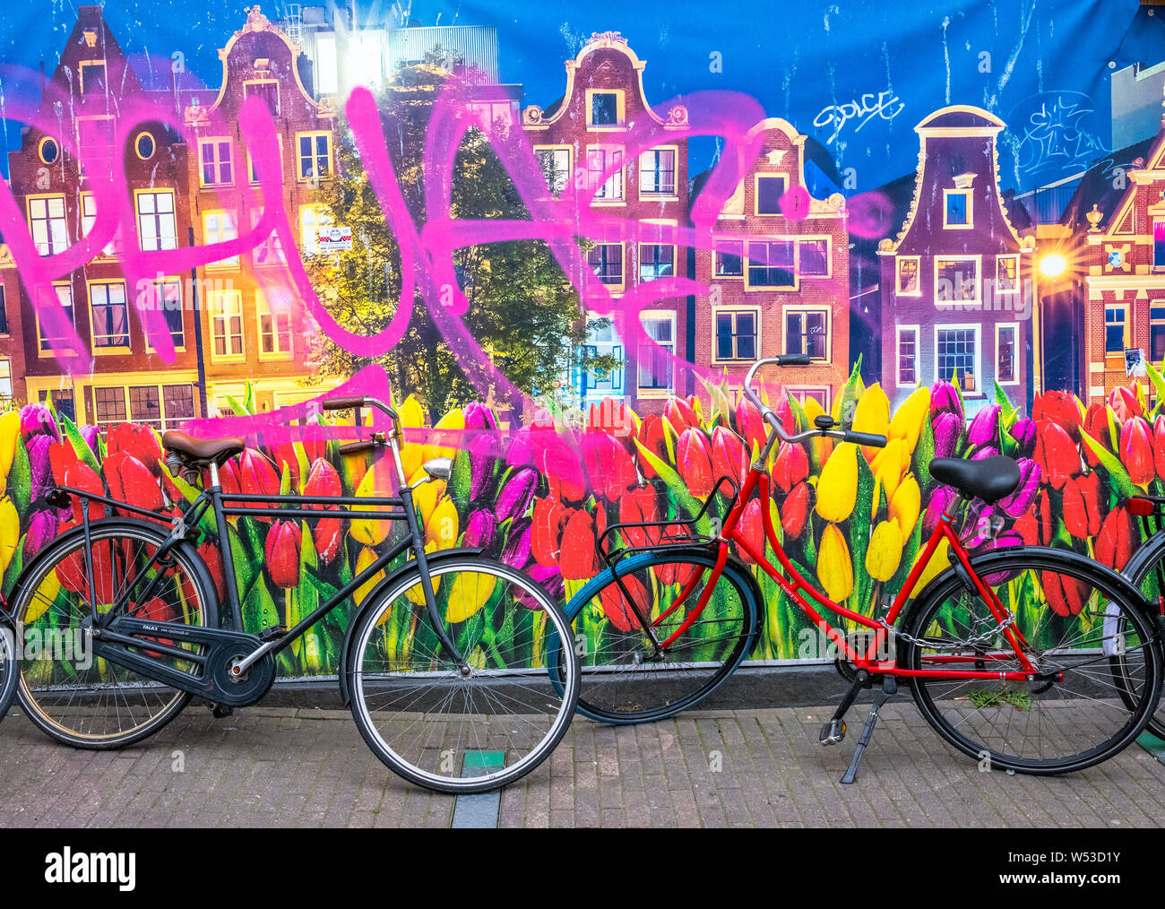 Les vélos hollandais en face d'une grande affiche de canal néerlandais du logement et de tulipes et de graffitis. Banque D'Images