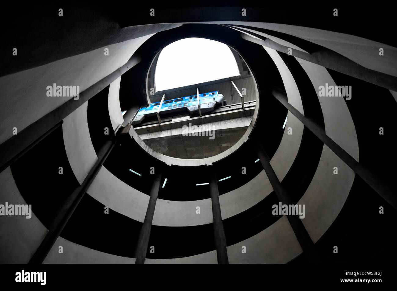 Un ver's eye view de la partie inférieure de l'hôtel de cinq étages de parking en spirale comme une rame de métro sur la ligne 2 du métro passe devant l'espace de stationnement à Chongqing Banque D'Images