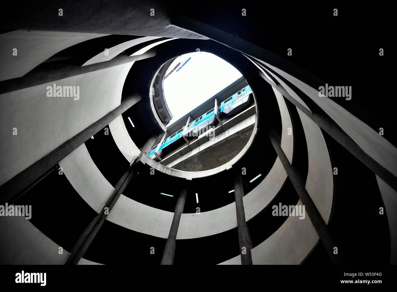 Un ver's eye view de la partie inférieure de l'hôtel de cinq étages de parking en spirale comme une rame de métro sur la ligne 2 du métro passe devant l'espace de stationnement à Chongqing Banque D'Images