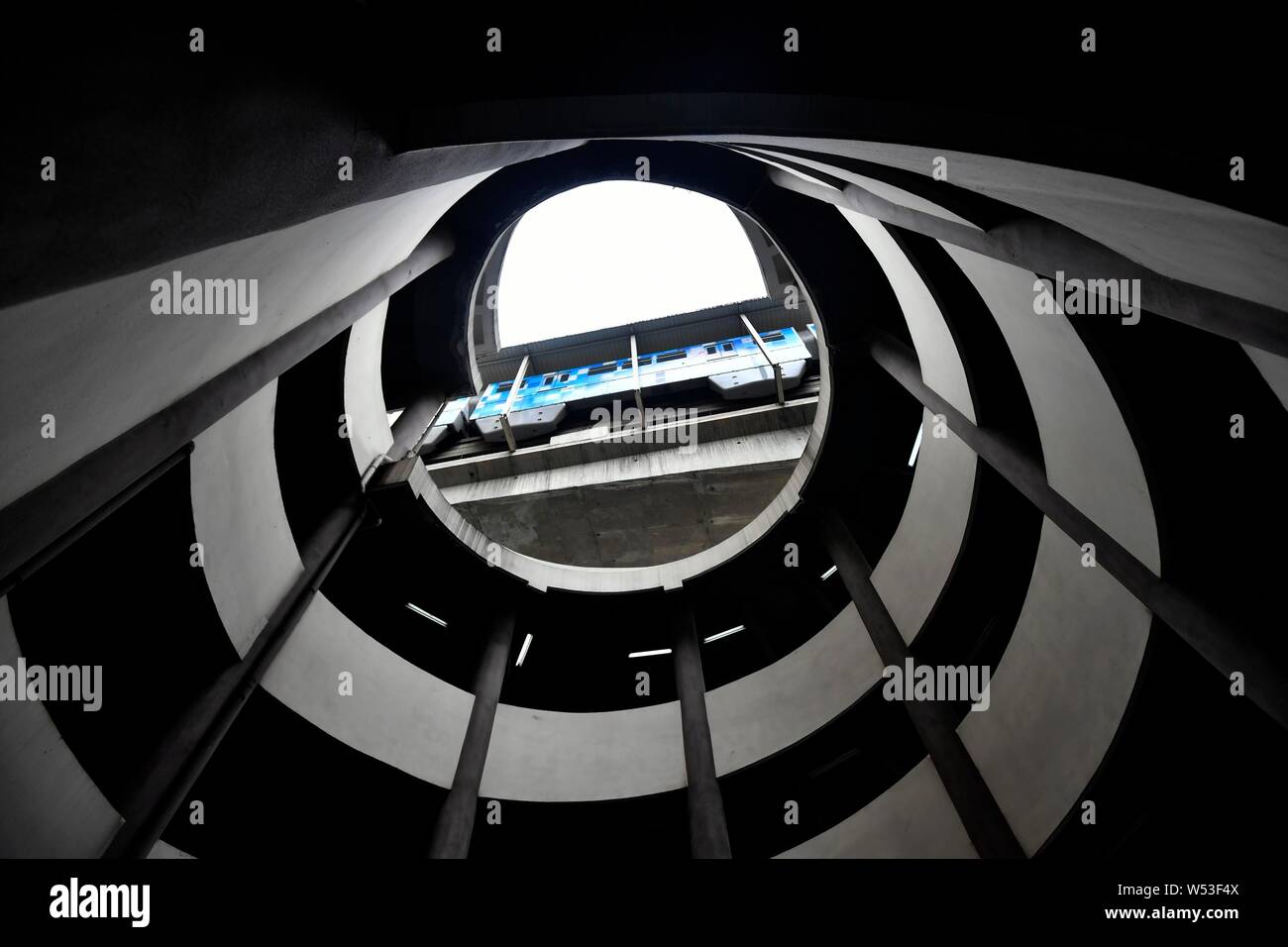 Un ver's eye view de la partie inférieure de l'hôtel de cinq étages de parking en spirale comme une rame de métro sur la ligne 2 du métro passe devant l'espace de stationnement à Chongqing Banque D'Images