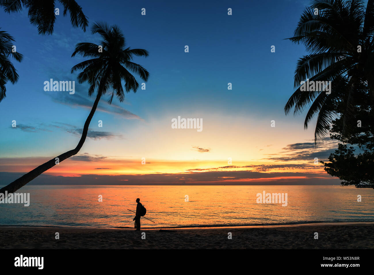 Choix de la route Concept, les rêves de l'avenir, le regret du passé. Silhouette d'un voyageur solitaire sur une plage tropicale sur un fond coucher de soleil. Banque D'Images