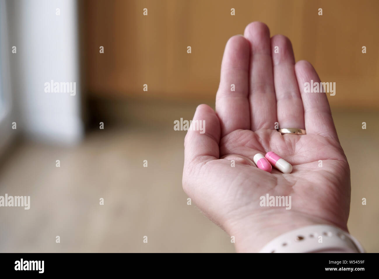 Une femelle adulte d'âge moyen qui tient deux, deux-pièces, de gélatine ou d'encapsulation gel couleur gélatine gélules de médicaments dans la paume de sa main. Banque D'Images