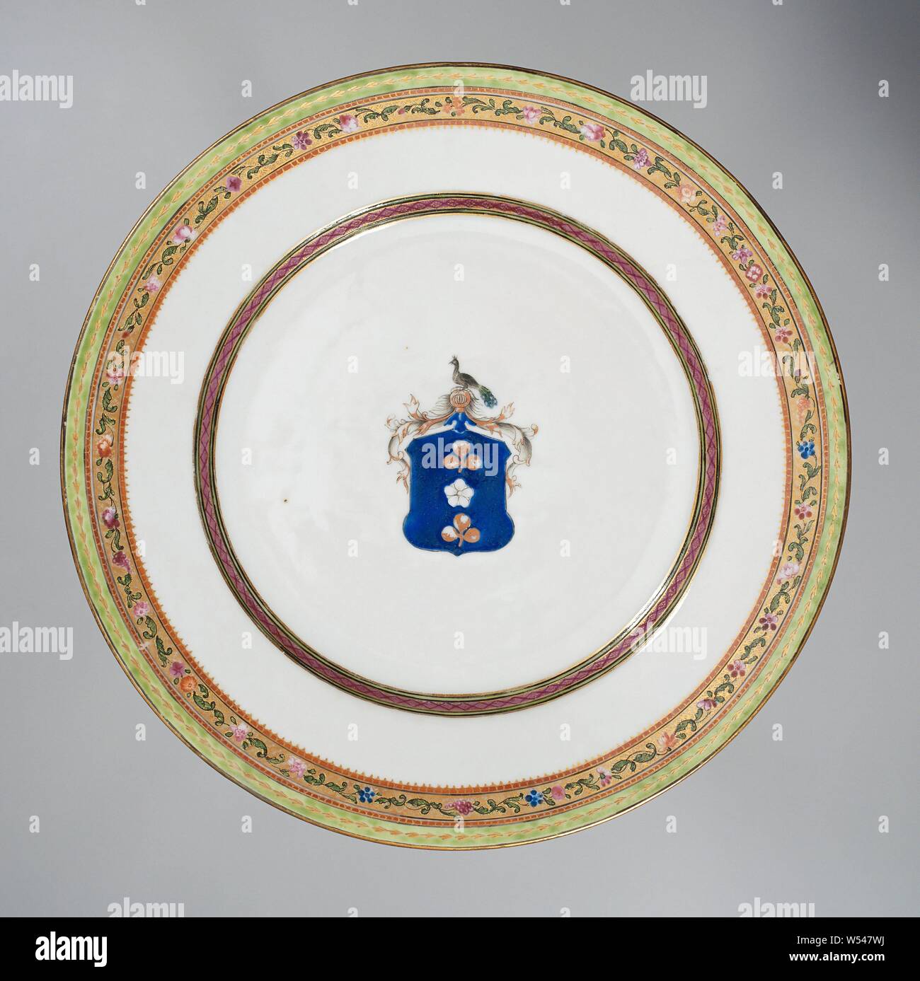 La plaque avec les armoiries de la famille Van Idsinga, assiette de porcelaine, peint sur la glaçure en bleu, rouge, rose, vert, noir et or. Sur le plateau les armoiries de la famille Van Idsinga avec un fond bleu avec une rose d'argent ou d'une fleur et une paire de trèfles d'or. Le casque signe est un paon et l'arme est entouré de vignes en feuilles, bande décorative sur le mur, la frontière avec une bande de motifs floraux morte couverte par deux rubans. Avec l'émail de porcelaine d'armes nucléaires. couleurs, anonyme, la Chine, l'c. 1775 - c. 1799, dynastie Qing-(1644-1912) / période de Qianlong (1736-1795) / Jiaqing-période (1796-1820 Banque D'Images