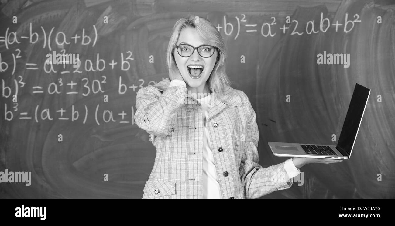 L'éducation est amusant. Enseignante portent des lunettes est titulaire d'ordinateur portable Internet surf. Les technologies numériques concept. Dame gaie éducateur avec ordinateur portable moderne tableau internet surf arrière-plan. Banque D'Images