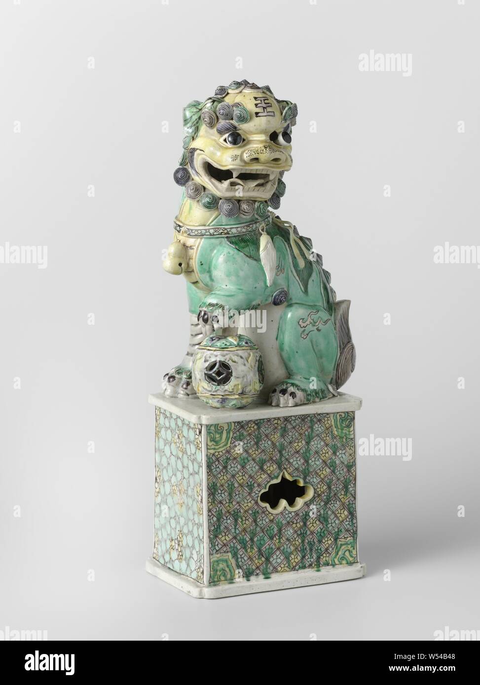 La figure d'un shishi, tasses d'image sur une base rectangulaire, haut, peint sur le biscuit avec du bleu, vert, jaune, Aubergine et noir. Sur le piédestal d'un shishi (lion chien) avec une patte sur une boule ajourée. Le socle est recouvert de nappes et de travail ouvert sur deux côtés, sous la forme d'un cartouche festonné et une direction générale de la pêche. Email sur biscuit en famille verte., anonyme, la Chine, l'c. 1700 - c. 1724, Qing Dynasty, Kangxi (1644-1912) / (1662-1722) période, porcelaine (matériau), peinture, h 38,3 cm l 14,5 cm × w 11 cm Banque D'Images