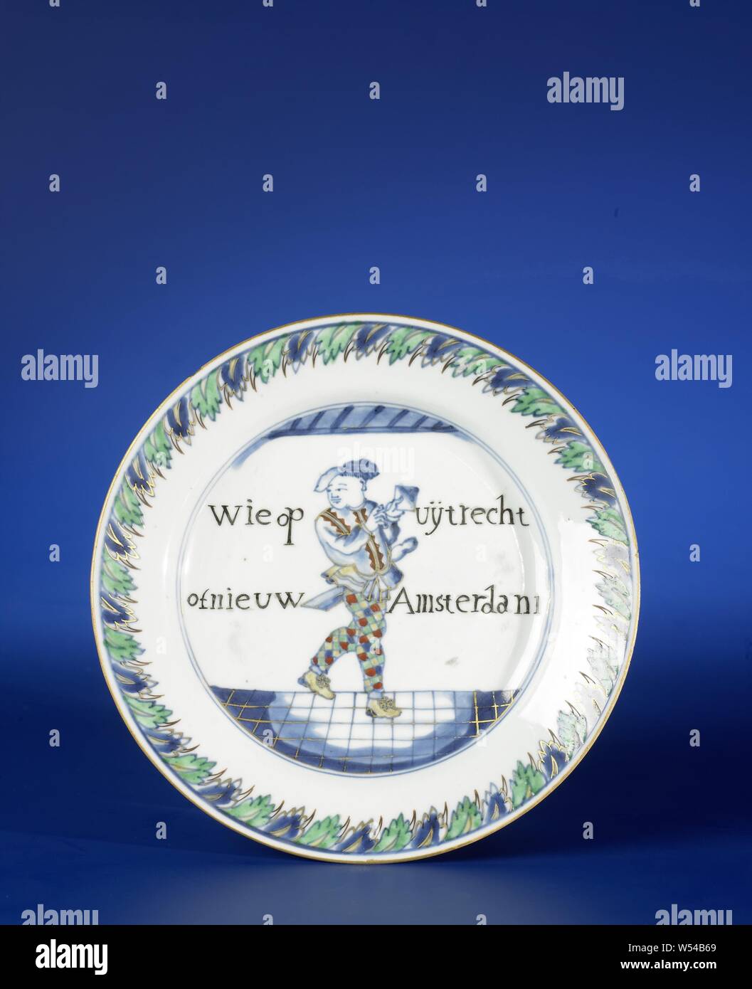 Plaque avec une figure caricaturale et inscription, assiette de porcelaine, peint en bleu sous glaçure et sur l'émail vert, noir et or. Sur l'étagère arlequin avec le texte : 'Qui sur Uijtrecht ou New Amsterdam', la frontière avec un motif décoratif. Le conseil d'action. La représentation européenne en bleu et blanc avec des couleurs d'émail., anonyme, la Chine, l'c. 1725 - c. 1749, dynastie Qing-(1644-1912) / Yongzheng-période (1723-1735) / période de Qianlong (1736-1795), Porcelaine, glaçure (matériel), le cobalt (minéral), de l'or (métal), la vitrification, H 3 cm d 21,2 cm d 11 cm Banque D'Images