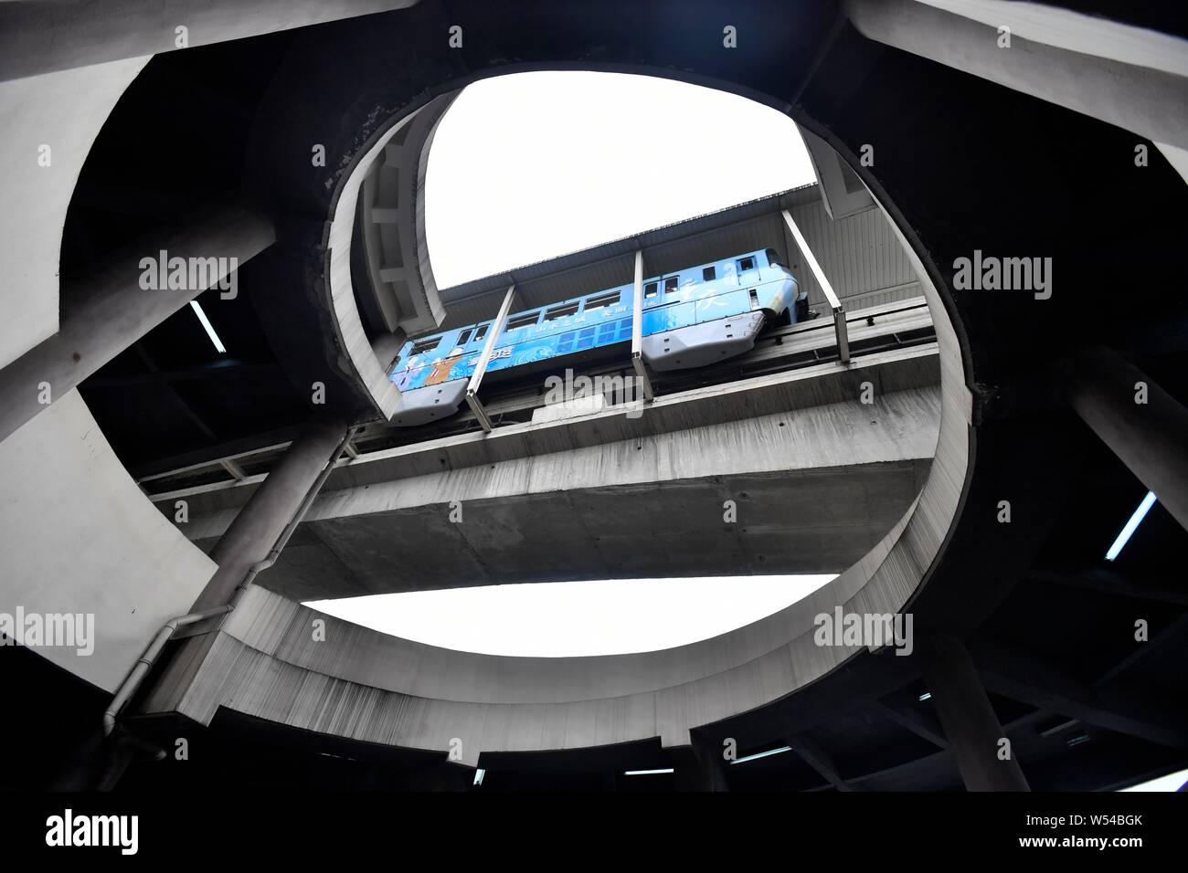 Un ver's eye view de la partie inférieure de l'hôtel de cinq étages de parking en spirale comme une rame de métro sur la ligne 2 du métro passe devant l'espace de stationnement à Chongqing Banque D'Images