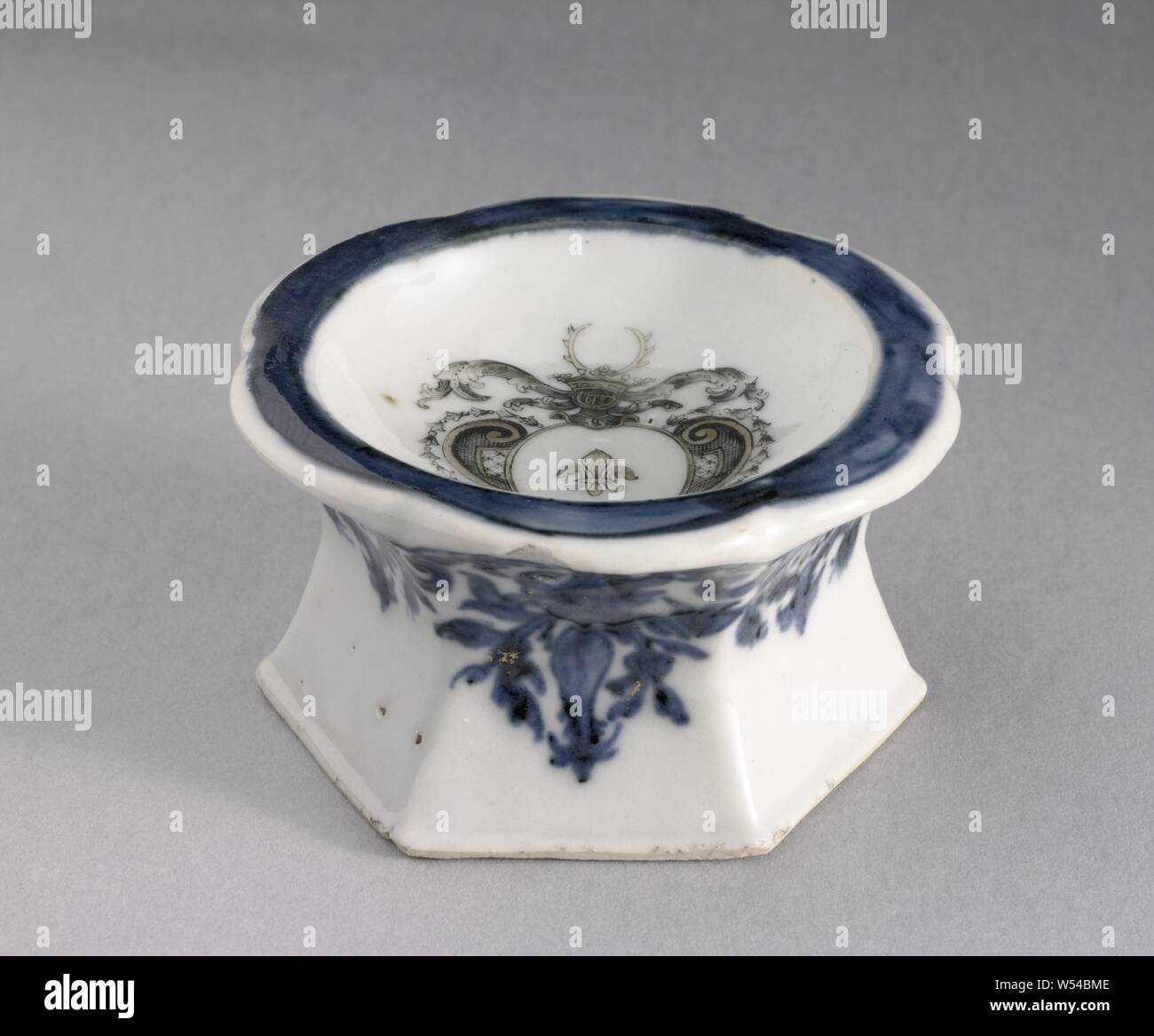 Grenier à sel avec les armes de la famille Swellengrebel, sel hexagonal baril de porcelaine avec six-bordure lobée, peint en bleu sous glaçure et sur l'émail noir et or. Au centre les armoiries de Hendrik Swellengrebel Français (Lily), le casque est signe d'une couronne avec un andouiller. Le gondolage et vrilles de feuilles autour de l'arme. La frontière avec une bande en bleu sous glaçure, la paroi latérale avec une bande de volutes florales dans le décor sous glaçure bleu et or. Porcelaine d'armes nucléaires en bleu et blanc et de couleurs d'émail, Hendrik Swellengrebel, anonyme, la Chine, l'c. 1725 - c. 1749, dynastie Qing-(1644-1912) / (1723-période Yongzheng Banque D'Images