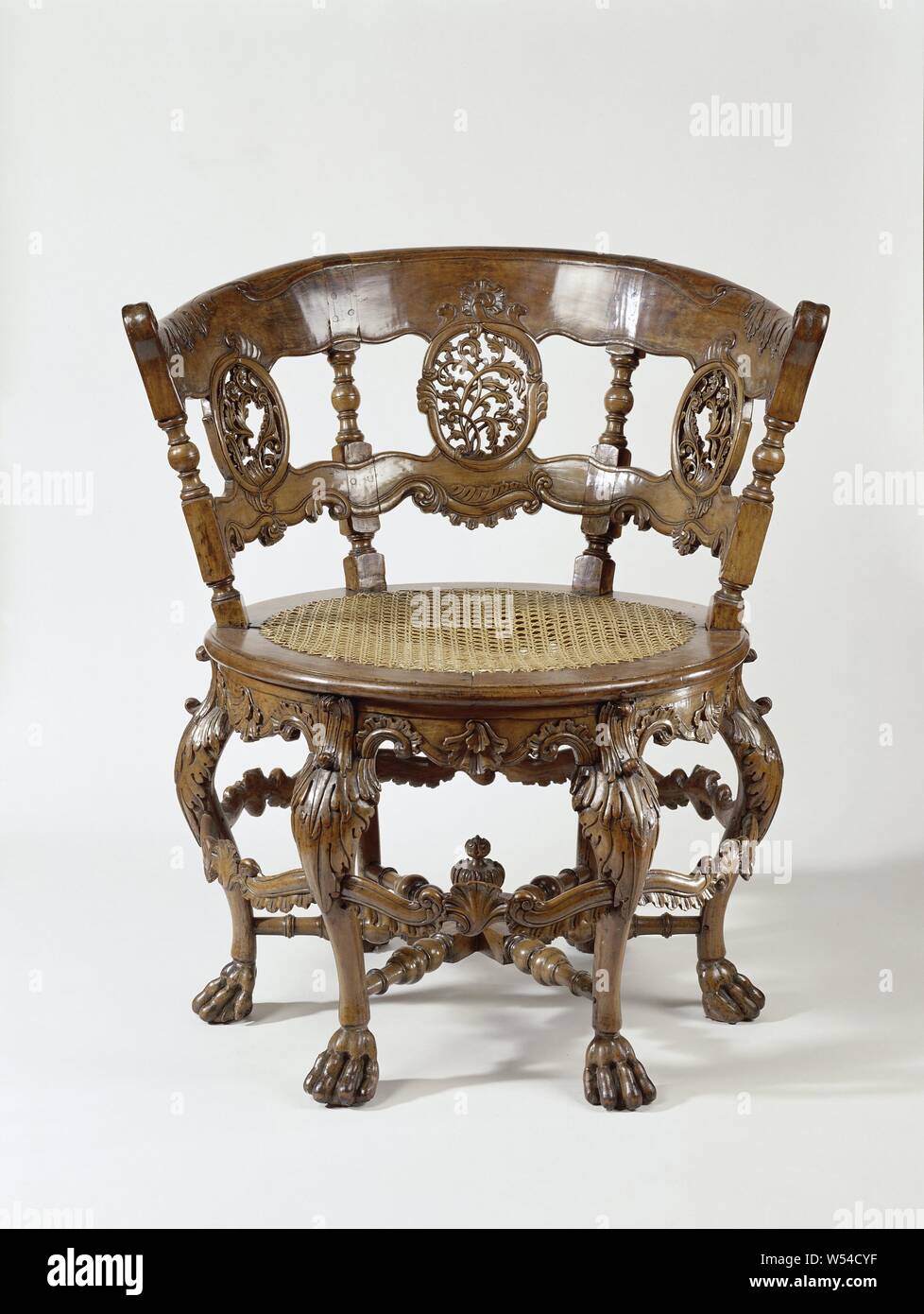 Chaise, fauteuil en teck ( ?), avec assise ronde en tissus de l'osier. Les  six pattes en forme de S fin en griffes et sont décorées avec un leafwork  au-dessus de l'enflure.