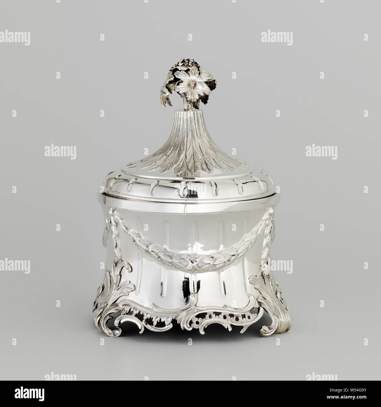 Boîte de tabac Tobacco jar, le pot rond, légèrement étranglées a un couvercle séparé. Le long du bord inférieur du pot court un cast, ajouré, contour ondulé avec C et S, les rocailles de volutes et qui est interrompu par les trois pieds en forme de feuille en fonte de la vigne. Le mur est cannelures et décorée d'un ruban, de guirlande de feuilles de laurier et de baies. Au-dessus de chaque bras apparemment, c'est attaché avec un clou, sur laquelle une ligne droite garland dépend. Un large bord droit, tourne autour de la partie supérieure. Le couvercle est constitué d'un bas, convexe, concave et une section à cannelures, une tour avec une pièce centrale de la décoration Banque D'Images