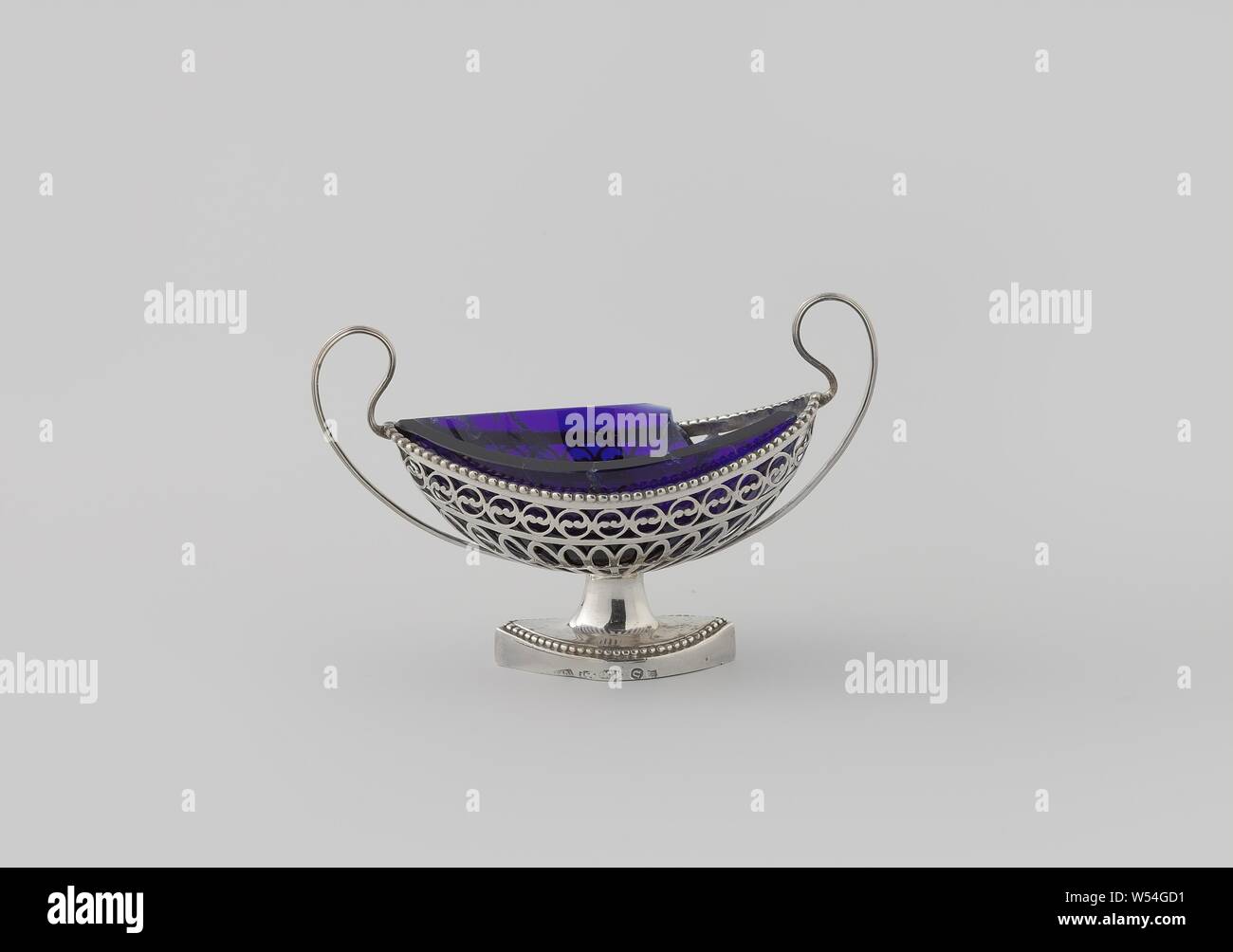 Bateau de sel, a fait ovale, avec mur en coupe et bords perlés, l'ovale a souligné, courbe navires, aux murs légèrement relevée sur les côtés, reste sur un ovale, également à la hausse sur les côtés, base de rajeunissement fortement sur une base fortifiée. Le corps est ouvert avec des fissures et des cercles constitués de deux C-volutes. Pearl frames exécuter autour du pied et le long du haut du corps. Le haut, les oreilles incurvées sont rainurés à l'extérieur. À l'intérieur de contenants sont verre bleu., Christiaan Mensink, Amsterdam, 1803, de l'argent (métal), verre, H 8,4 cm × w 12,6 cm × D × w 61,5 5,5 cm Banque D'Images