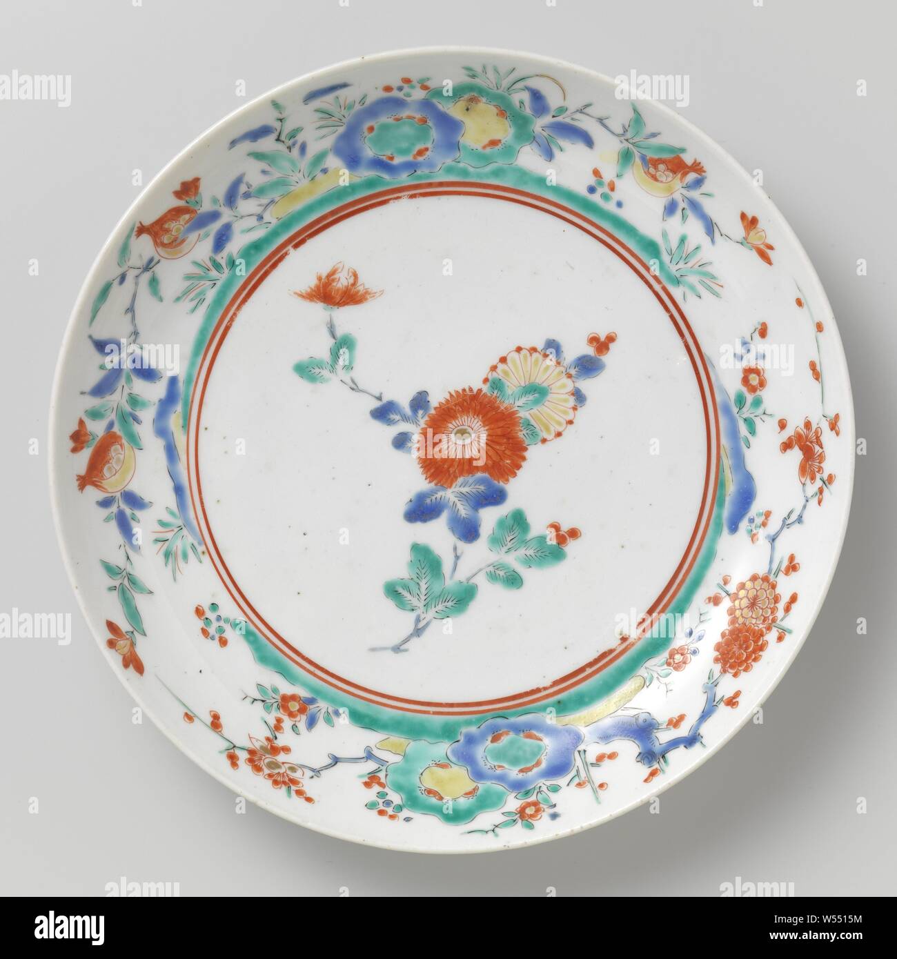 Plat de soucoupe avec plante à fleurs, plat en porcelaine peinte sur l'émail en bleu, rouge, vert, jaune, noir et or. Sur l'étagère un chrysanthème direction générale. La paroi interne avec deux fois des rochers avec des plantes à fleurs (prunus, grenade). Ancienne étiquette au bas avec 'Westendrop / 51 collection'. Quatre proen sur le fond. Style Kakiemon., anonyme, le Japon, l'c. 1675 - c. 1685, période Edo (1600-1868), Porcelaine, glaçure (matériel), de l'or (métal), la vitrification, D. 22,5 cm Banque D'Images