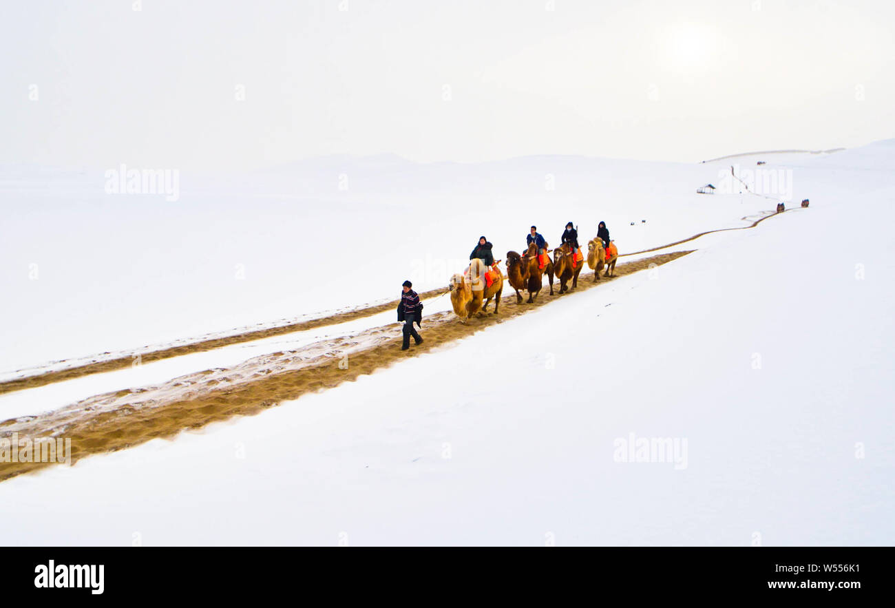 Les touristes monter des chameaux dans le désert de Gobi dans le Croissant de lune (Yueyaquan) et le chant des montagnes de sable au cours de l'endroit pittoresque Chine Banque D'Images