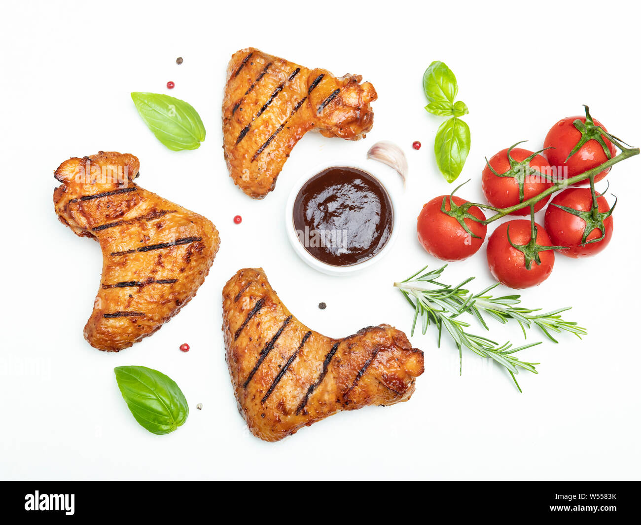 Ailes de poulet grillées, sauce barbecue brown rosemary basilic tomates épices sur fond blanc Banque D'Images