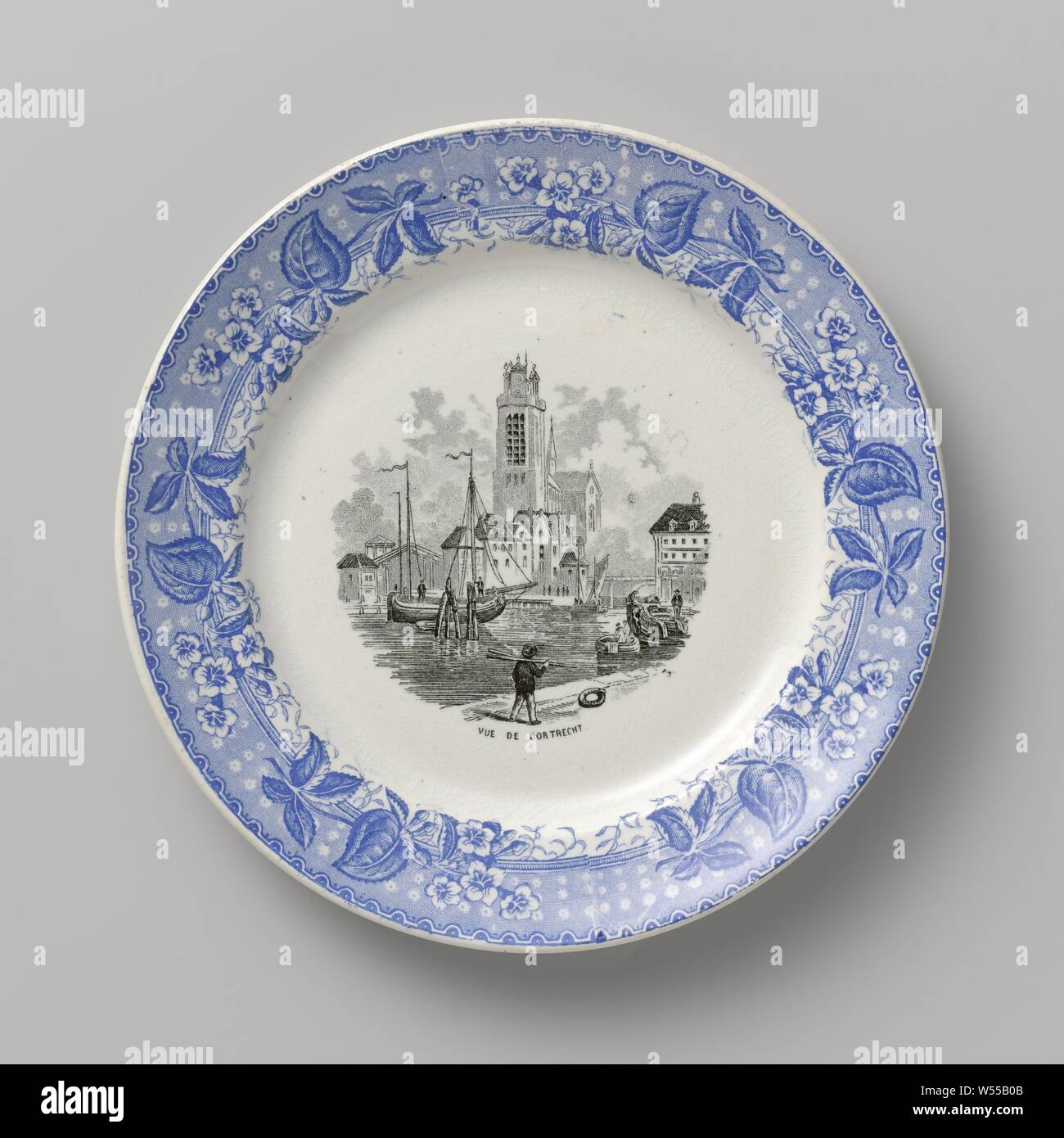 La plaque avec une vue de Dordrecht sur le plateau, la plaque de la faïence avec décor transfert noir et bleu. Sur la télévision en noir transférer imprimer une vue de Dordrecht. Ci-dessous le montrent le texte : VUE DE DORTRECHT. Le bord de la plaque avec une impression transfert bleu y compris le bleu des fleurs et des feuilles., N.V. Société Céramique, Maastricht, ch. 1863 - c. 1958, argile, H 2,1 cm × d 19,8 cm Banque D'Images