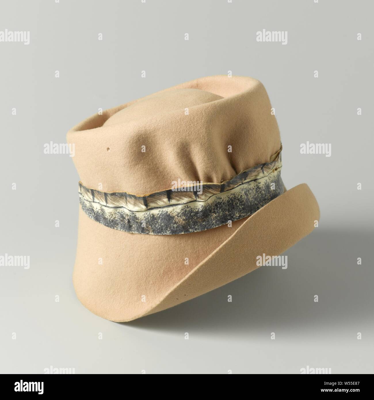 Cloche de feutre jaune doux ou beige et un bracelet en cuir qui a été peint, Cloche de sentir dans la couleur beige ou jaune pâle, avec une lanière de cuir peint avec un motif de plumes. À l'intérieur d'une étiquette qui indique : KATJA ROBINSKI. AMSTERDAM, Katja Robinski, Amsterdam, ch. 1958 - c. 1965, d'un feutre (textile), cuir, peinture, H 13 cm × d 24 cm Banque D'Images