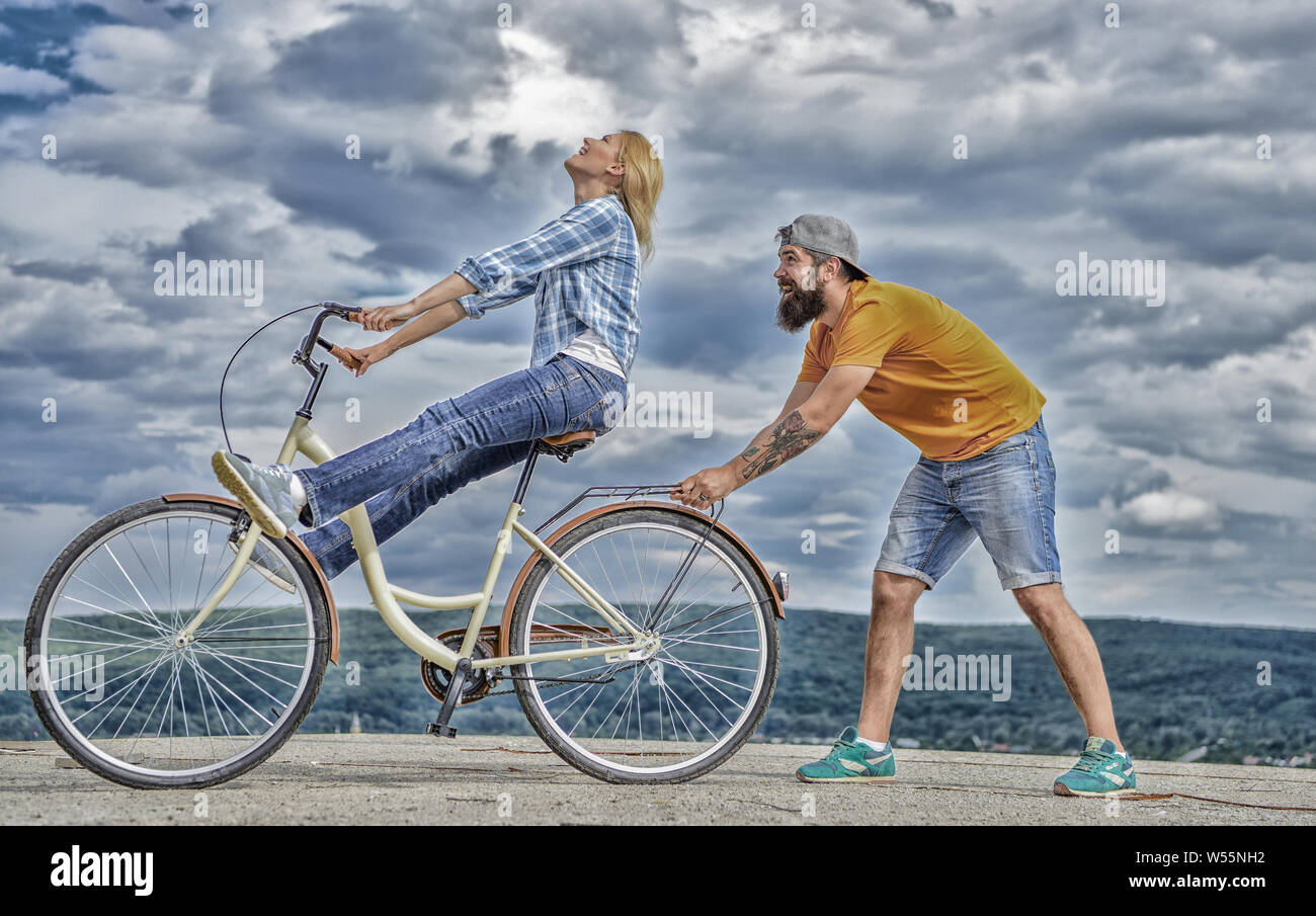 L'homme aide à garder l'équilibre et faire du vélo. Comment apprendre à  faire du vélo comme adulte. Vélo fille tandis que l'appui de son petit ami.  Des promenades en vélo femme fond