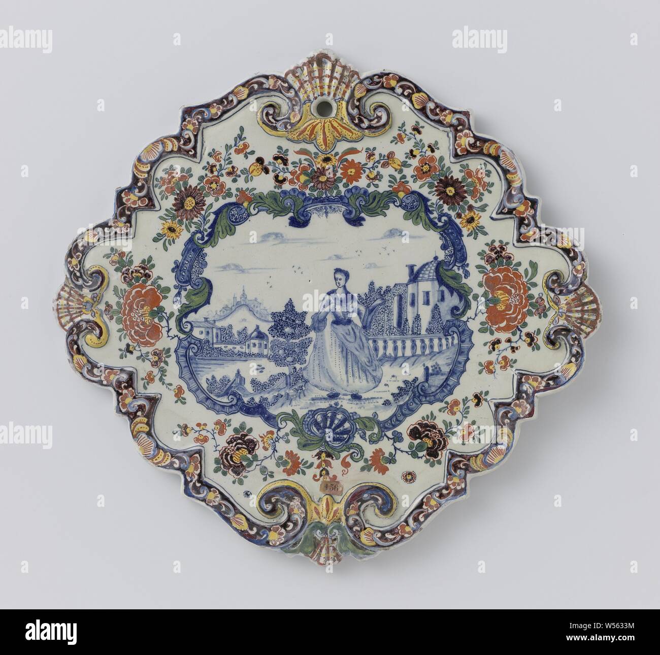 Assiette en forme de diamant, avec bord cannelé. À l'intérieur d'une bordure de fleurs multicolores une scène peinte en bleu d'une dame dans un jardin, Faque la plaque. Peint avec une figure féminine dans un jardin en bleu, encadré par une bordure de fleurs multicolores., anonyme, Delft, c. 1750 - c. 1775, h 29,5 cm × 31,0 cm × w d 2.0 cm Banque D'Images