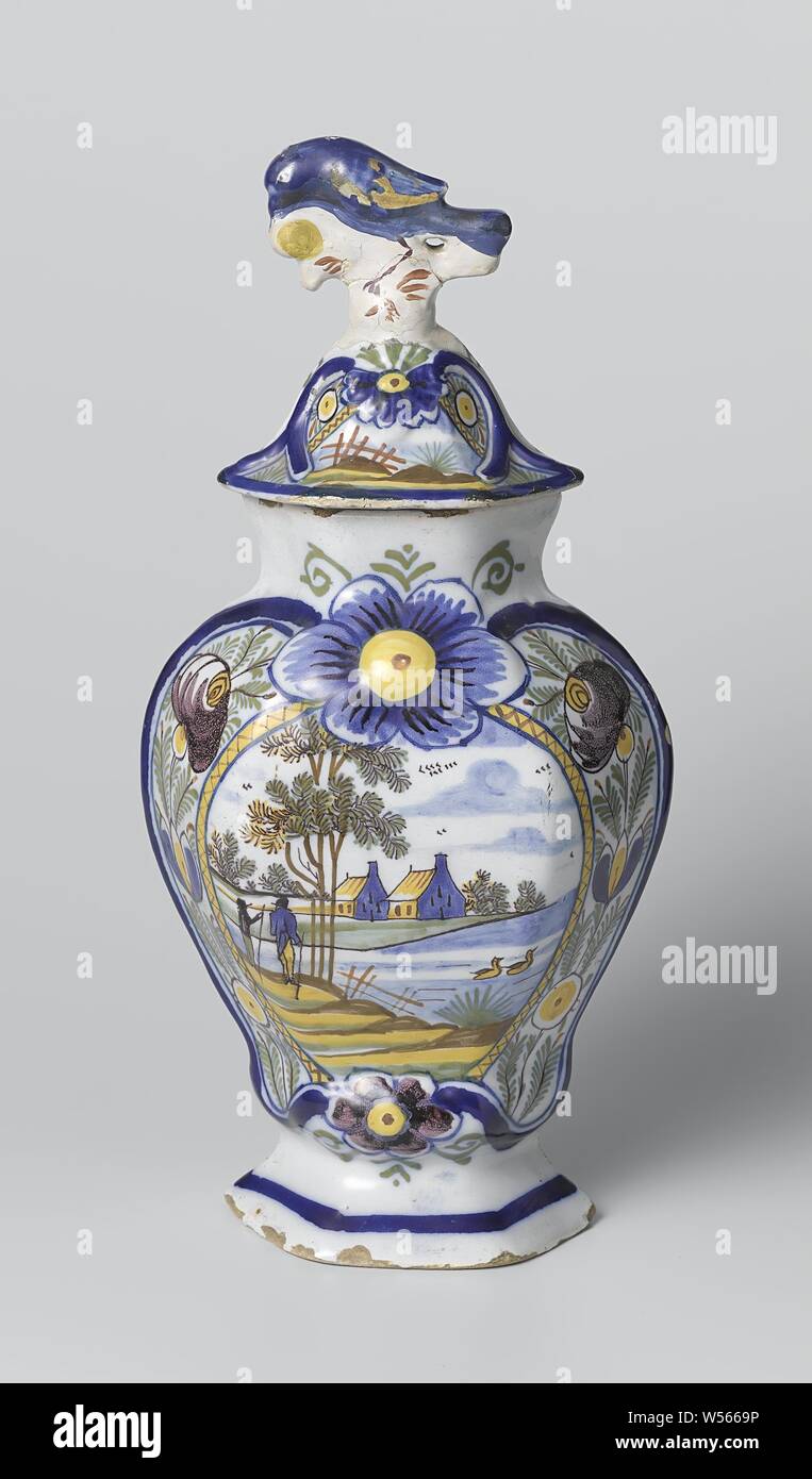 Jarre recouverte, Pot de faïence multicolores. Un cartouche avec deux maisons dans un paysage aux couleurs bleu, jaune, vert, brun et violet est peint sur le pot. Le bouton du couvercle est un oiseau à picorer un fruit. Le pot appartient à une tasse avec jambes identiques., De Vergulde Blompot, Delft, ch. 1810 - c. 1840, faïence, émail étain, h 32,0 cm Banque D'Images