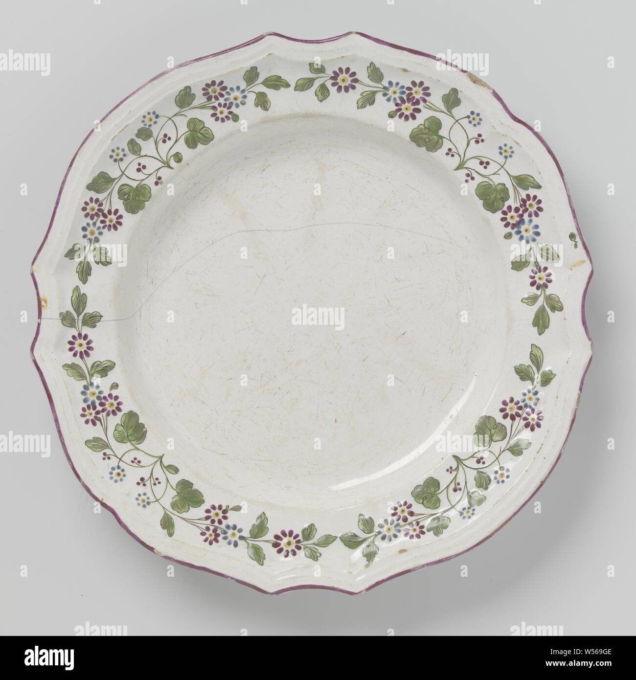 Plat rond avec bord cannelé et peinture multicolore de volutes, fleurs plat rond de faïence peint multicolores. Le plat a une bordure festonnée sur lequel défile floral sont peints. Les fleurs sont peintes dans les couleurs violet et bleu et ont des feuilles vertes., anonyme, Allemagne, ch. 1800 - c. 1860, faïence, émail, d'étain 29,5 cm × H 3 cm Banque D'Images