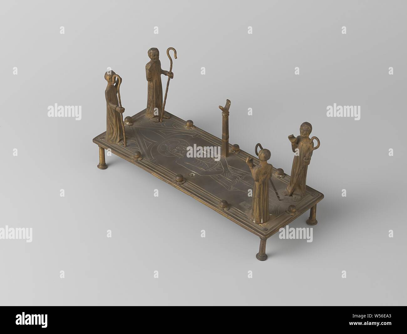 Ostensorium-relique, l'objet se compose d'une plaque ornée d'une figure du Christ, qui est placé sur quatre pieds et quatre chiffres sur lesquels l'homme avec des bars sont placés sur les coins, tenant leur main droite ou gauche, dans lequel ils ont probablement porté quelque chose ensemble. La plaque est décorée de huit rosettes. Fourche deux stands ont été placés dans le milieu, dont l'un est manquant., anonyme, West-Europa, ch. 1800 - c. 1900, le laiton (alliage), gravure, h 11,3 cm × 22,3 cm × w d 9 cm Banque D'Images