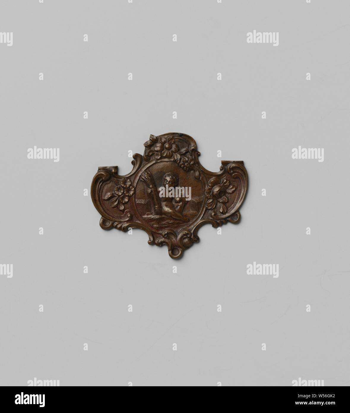 Modèle pour un élément décoratif d'une chatelaine. La plaque d'un modèle de moule est fourni avec un ornement rococo et fleurs, un médaillon avec un putto avec gerbe de maïs et d'une faucille. En bas le long des bords plus ovale trois liens de liens., anonyme, Amsterdam, c. 1750 - c. 1775, le cuivre (métal), h 3,2 cm × 3,9 cm Banque D'Images