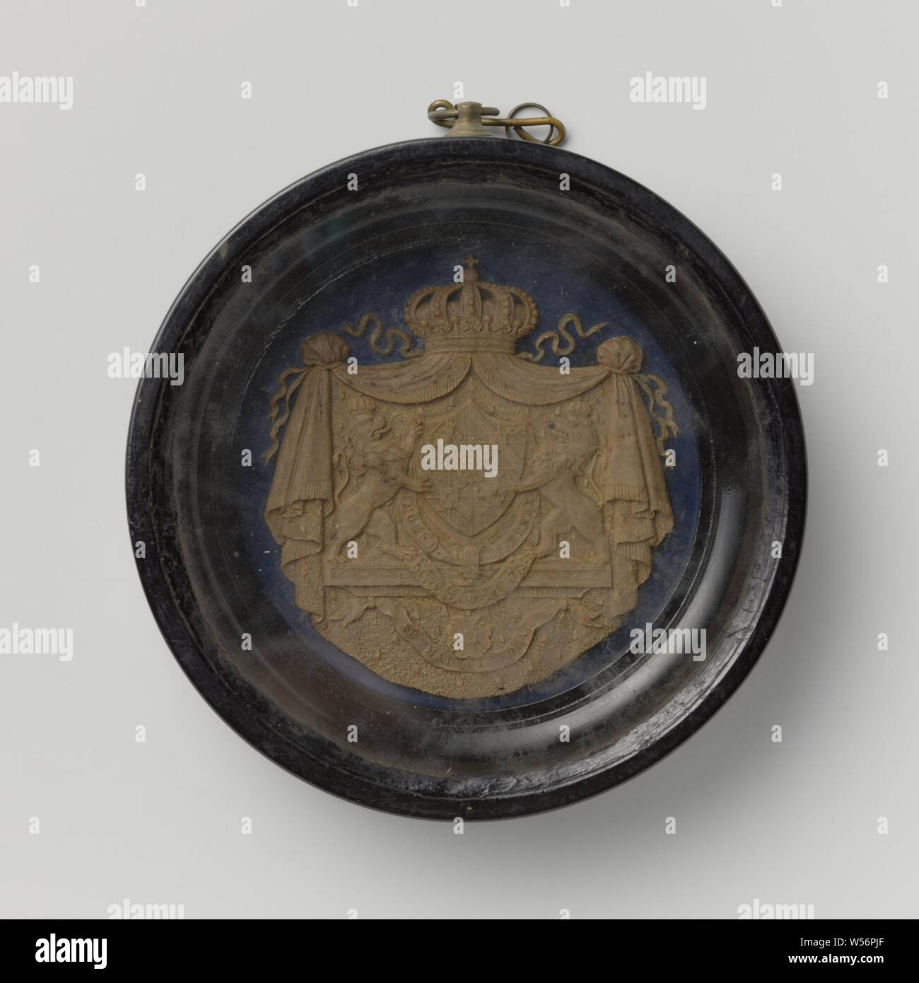 Armoiries du roi Guillaume Ier, armoiries de William I Frederik, Roi des Pays-Bas dans le cadre de la ronde cadre noir avec crochet et derrière le verre. Deux lions couronné armoiries de maintenir élevé. Ci-dessous, boucle de 'HONI' et 'pense'. Vous trouverez ci-dessous deux banderoles, dont une est illisible. La basse 'Je maintiendrai". Des rideaux drapés sur les deux côtés au-dessus qui couronne. Sur fond bleu. Sur l'arrière du cadre d'une étiquette avec le texte collé, Frederik Willem I (Roi des Pays-Bas), anonyme, Pays-Bas, 1815 - 1840, le bois (matière végétale), verre, cire, d 15,2 cm × D × 3,2 cm H 21 cm Banque D'Images