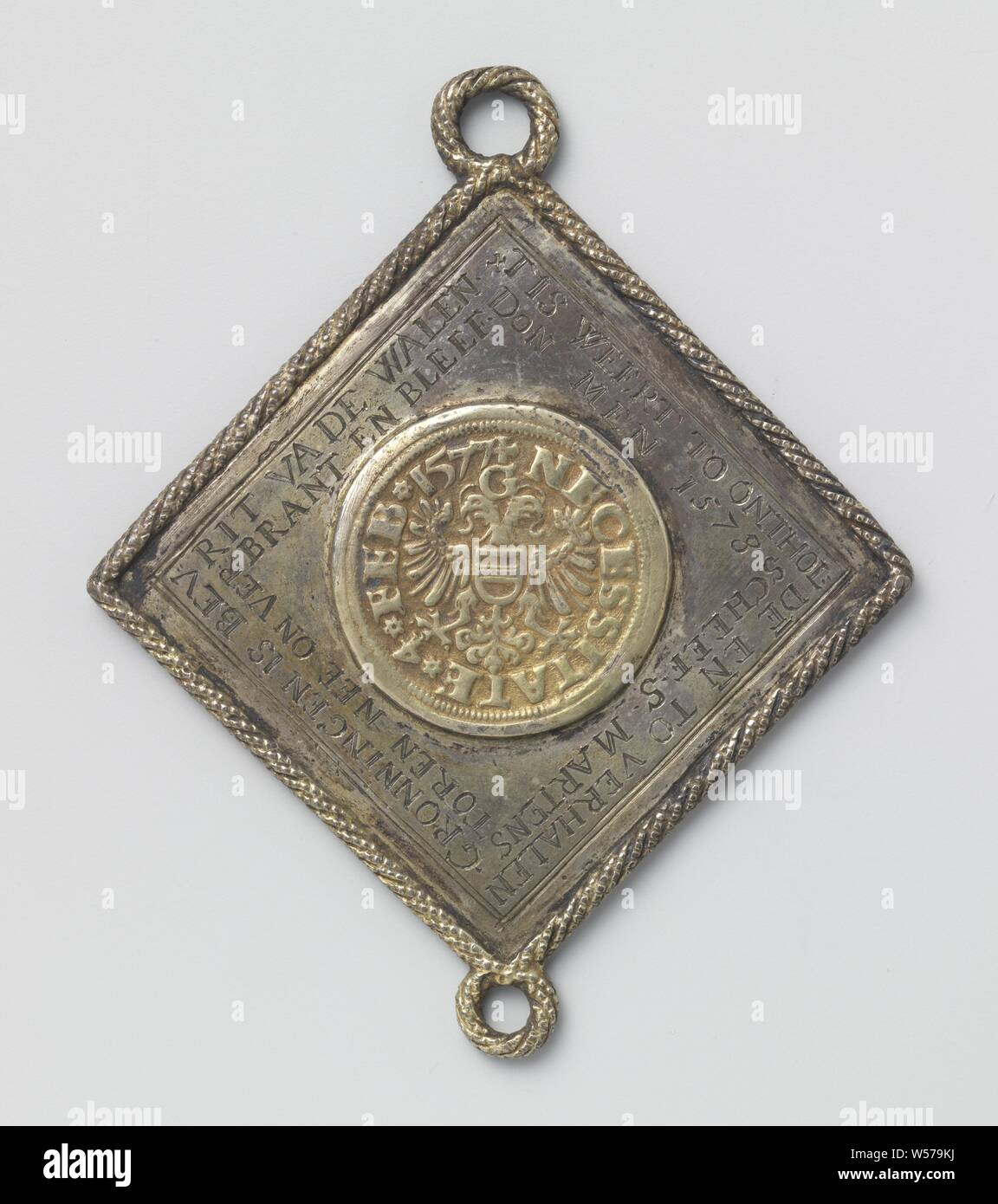 Siège de Groningue, médaille de l'histoire faite d'un thaler, royal coupe ronde et dorée, monnaie d'urgence situé sur une plaque en forme de losange monté dans un câble frontière avec un oeil ci-dessus et ci-dessous. Avers : Devise : aigle bicéphale avec armoiries de poitrine sous la lettre G à l'intérieur de l'inscription, sur la plaque d'argent : deux lignes de texte : c'est encore caché et dit à Gronningen est libre des hommes murs Don 1578 crooked S. martens aucun tour et débridée est resté '. Retour : peint le portrait de femme, à gauche : Deux blasons united sous casque couronné, Groningen, Wijntgens Eeltz, Balthasar, Jan-1577 Banque D'Images